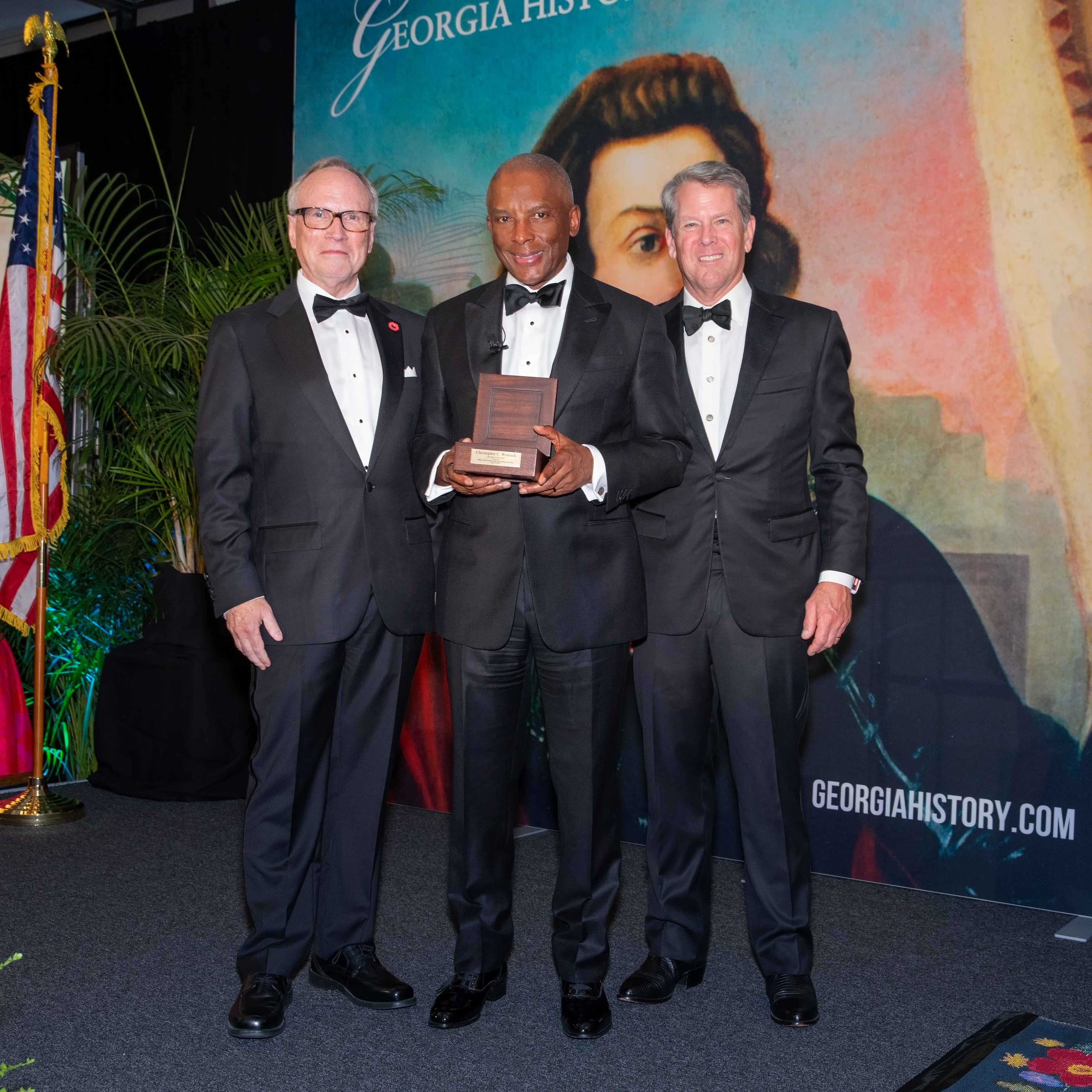 Dr. W. Todd Groce (left), president and CEO of the Georgia Historical Society and Gov. Brian Kemp (right) induct Chris Womack, chairman, CEO and president of Southern Co. as a 2026 Georgia Trustee on April 18, 2026, in Savannah. (Courtesy of Georgia Historical Society)
