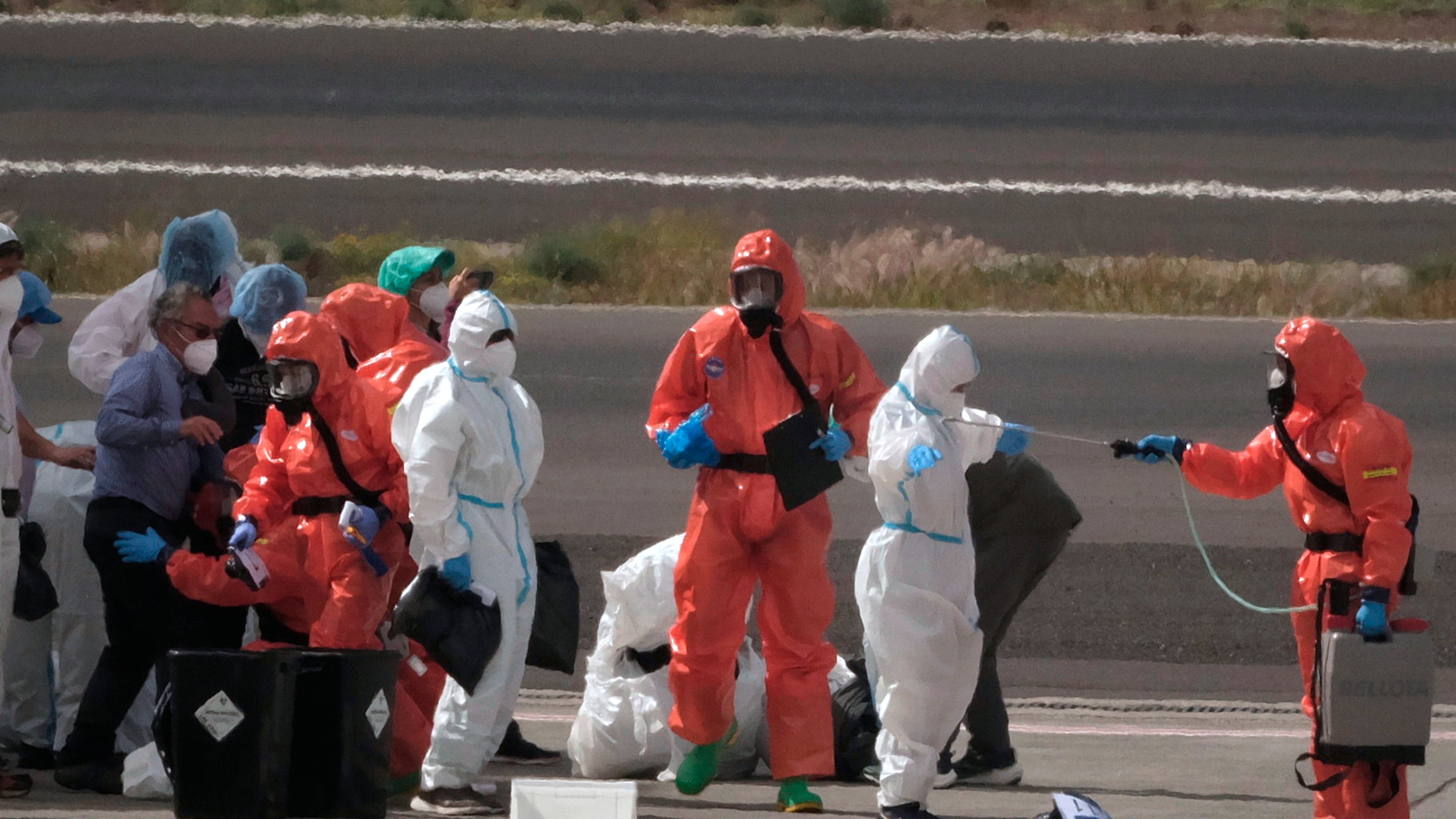 Passengers are sprayed with disinfectant by Spanish government officials before boarding a plane after disembarking from the hantavirus-stricken cruise ship MV Hondius at Tenerife airport in the Canary Islands, Spain, Sunday, May 10, 2026. (Arturo Rodriguez/AP)