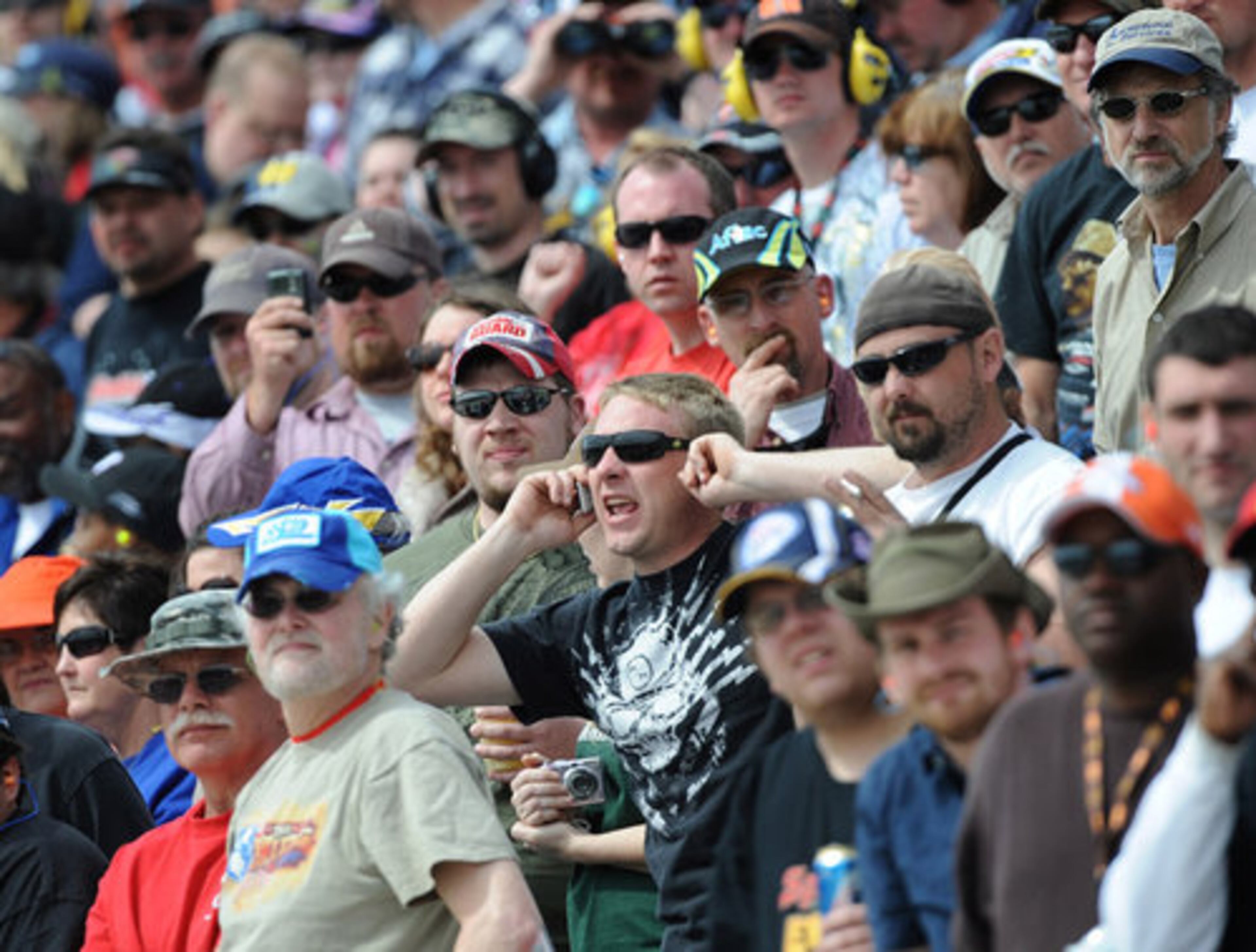 Undeterred by the sound of the racetrack, a fan tries to talk on a cell phone.