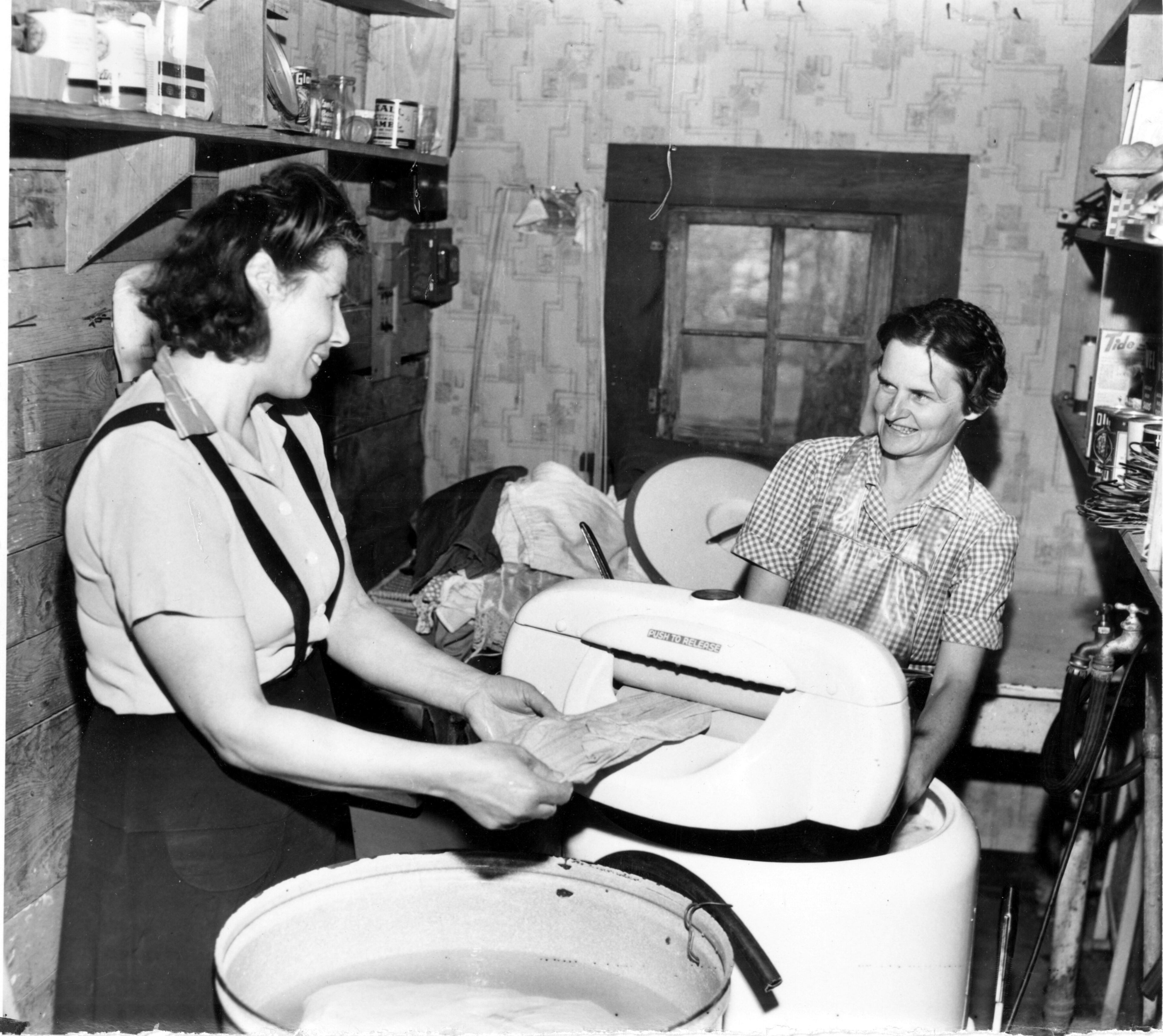 Mrs. T. W. Nalls, the farmer's wife, shows her refugee guest, a displaced person from Estonia, Mrs. Kivivare (left), how to do American washing.