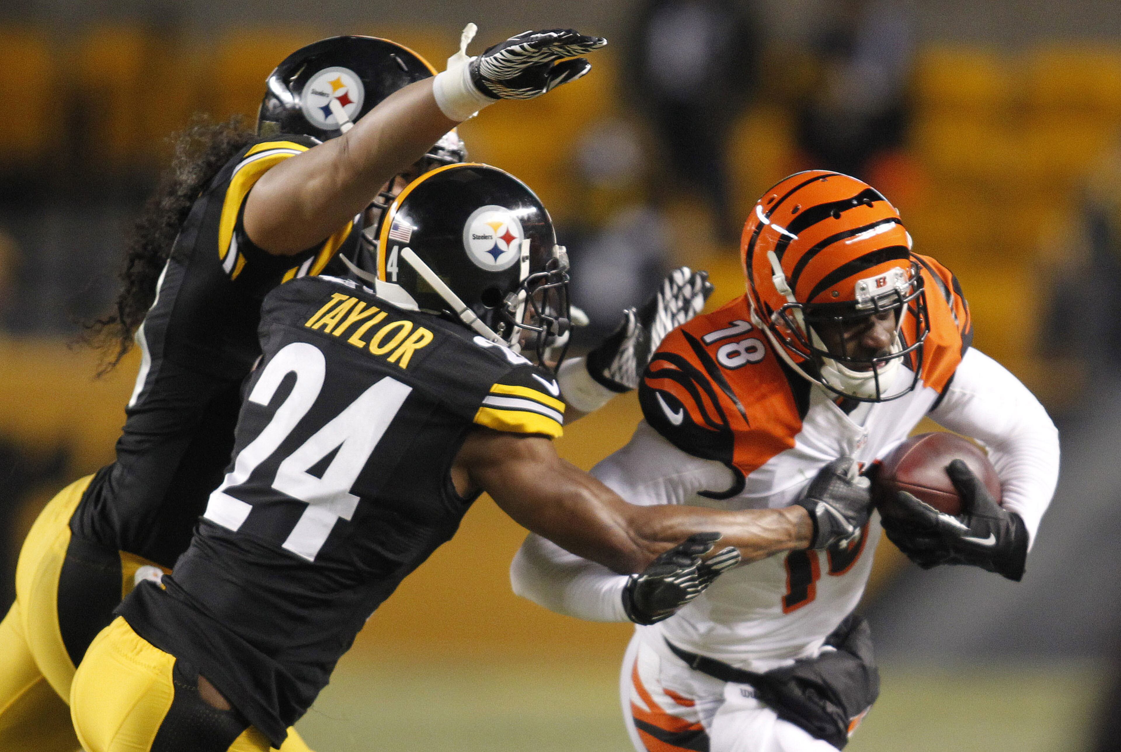 Cincinnati Bengals wide receiver A.J. Green (18) runs with the ball as Pittsburgh Steelers strong safety Troy Polamalu (left) and cornerback Ike Taylor (24) attempt to tackle during the third quarter at Heinz Field. The Steelers won 30-20.