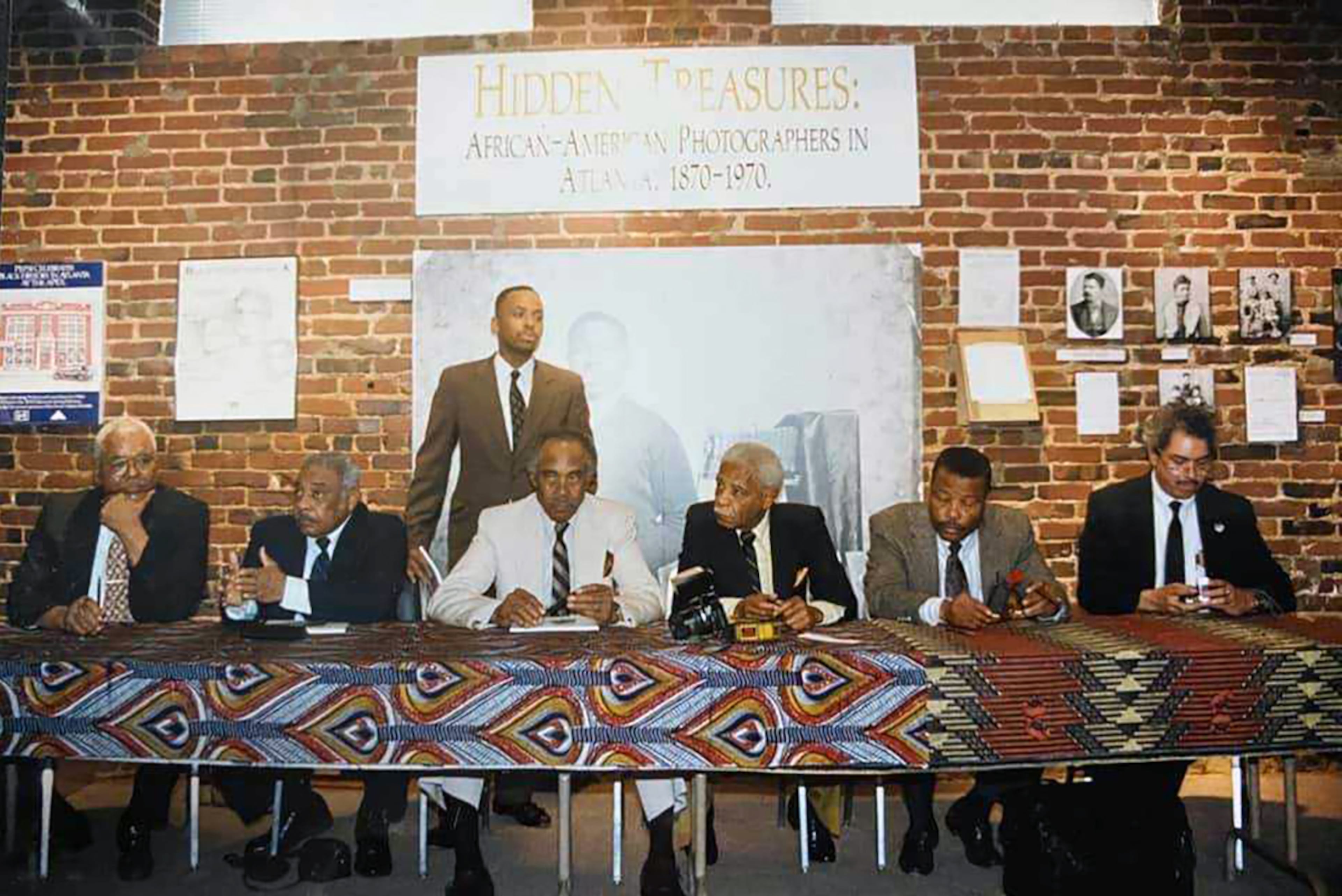 Herman "Skip" Mason (standing) curated an exhibit in 1991 called “Hidden Treasures: African American Photographers in Atlanta” that included The Journal's first Black reporter and longtime photographer Harmon Perry. Photographers W.A. Scott III (from left), George H, Rice Sr., T. Maurice Pennington, Harmon Perry, Robert S. Johnson and Julius Alexander were featured. (Courtesy of Herman Skip Mason Jr.)