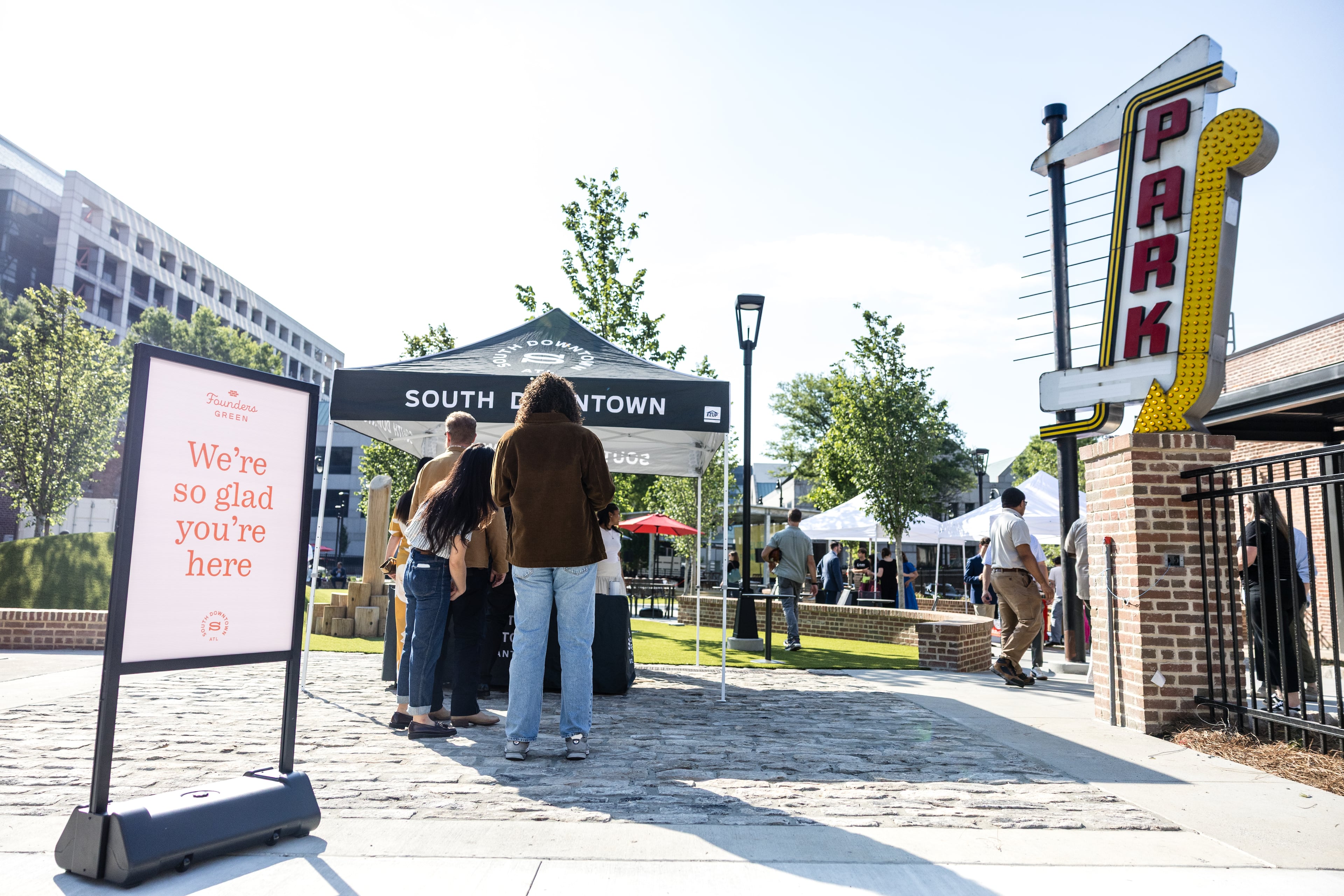 The entrepreneurs leading the transformation of several blocks of South Downtown held a ribbon cutting for their first green space on May 20. The sign to the left was excavated from the site.