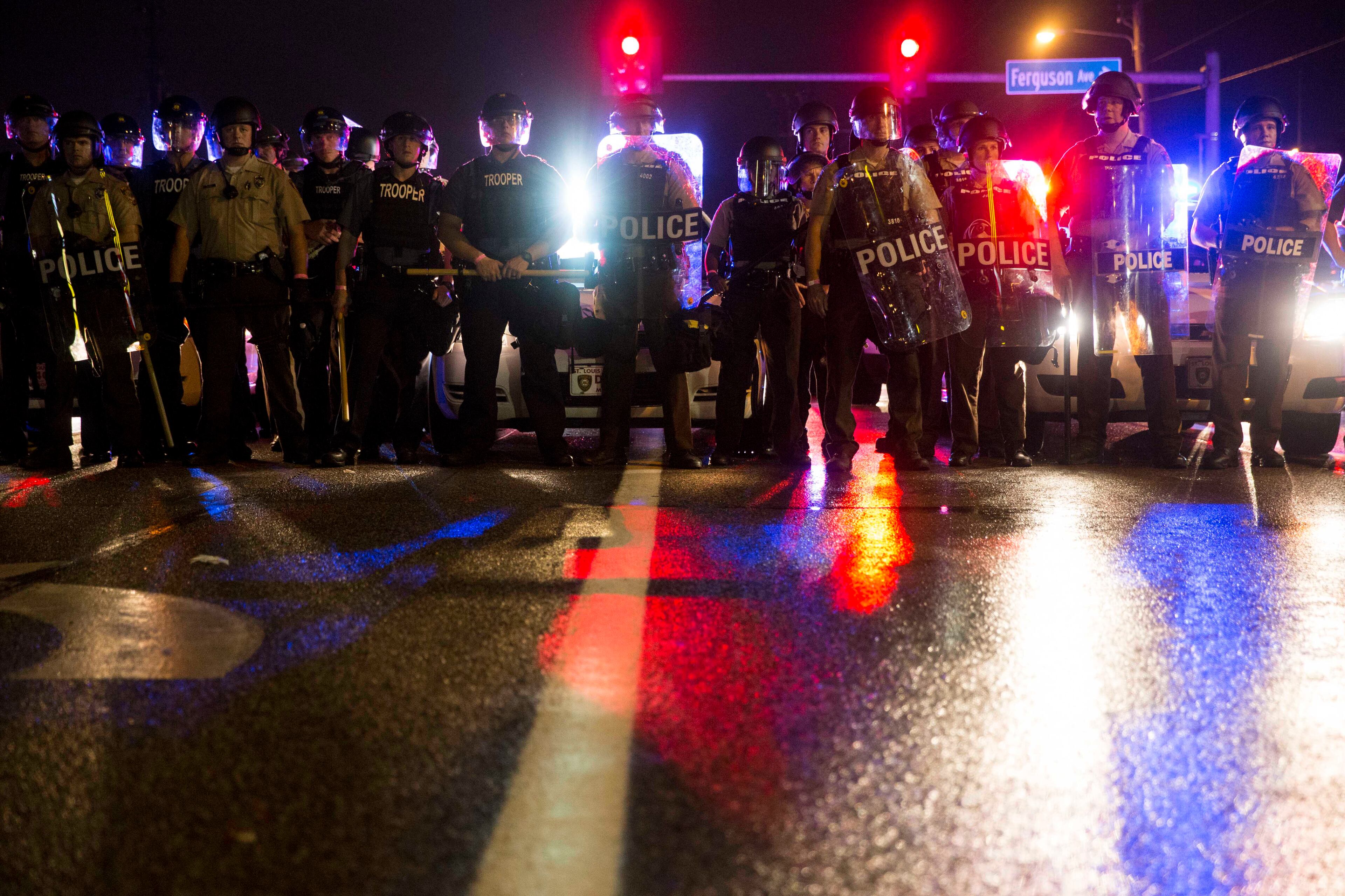 Police officers face off with protesters on West Florissant Avenue on the anniversary of Michael Brown's death in Ferguson, Mo., Aug. 9, 2015. A day of peaceful protest commemorating the killing of an unarmed black teenager by a white police officer one year ago ended in gunfire late Sunday. A St. Louis County police officer was involved in the shooting, the department said. (Whitney Curtis/The New York Times)