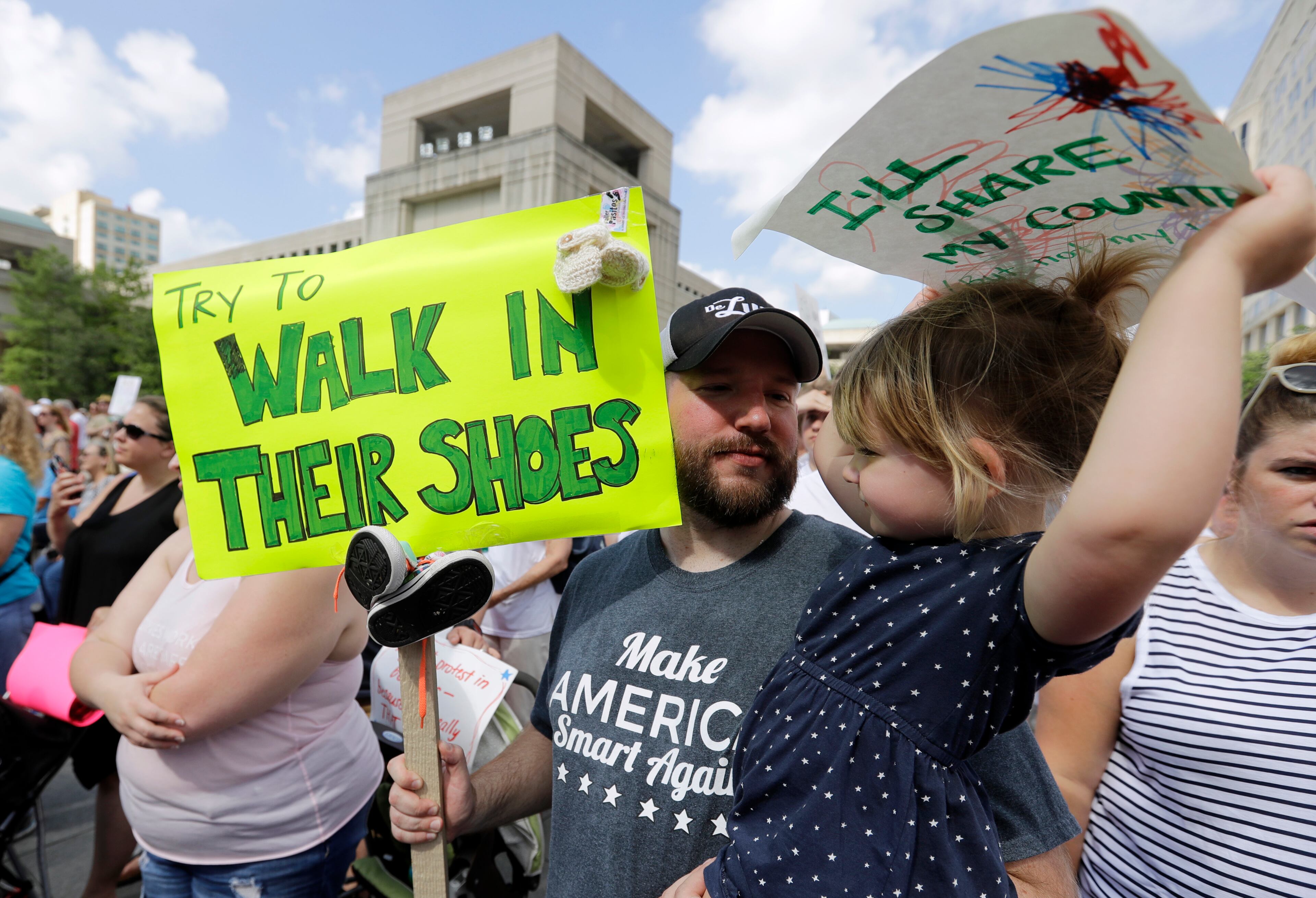 Scott Burns, holds his daughter, Annelle, listen to speakers during a protest of the Trump administration's approach to illegal border crossings and separation of children from immigrant parents at the Statehouse, Saturday, June 30, 2018, in Indianapolis.