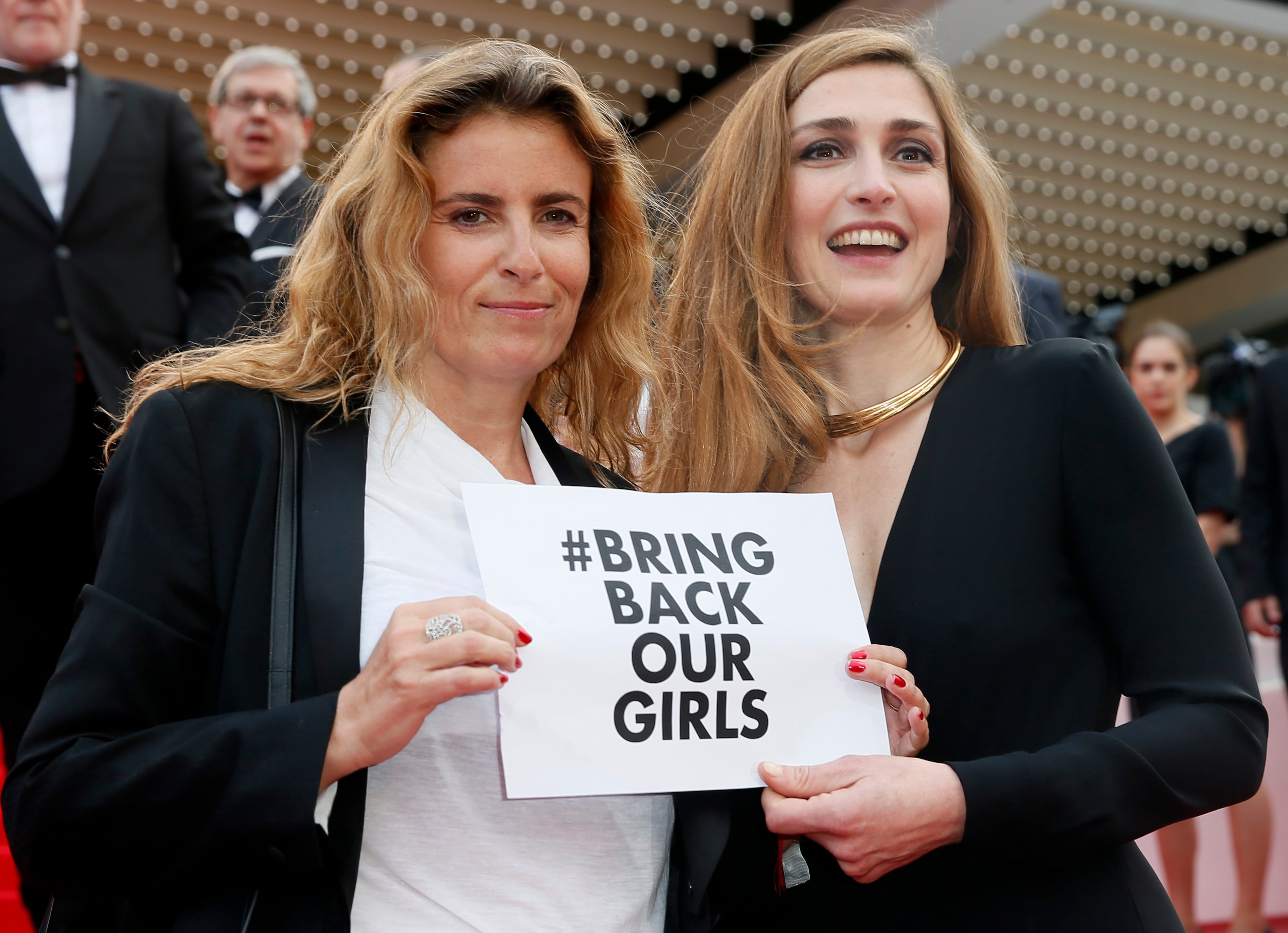 Actress Julie Gayet, right, and director Lisa Azuelos hold a sign reading "bring back our girls", part of a campaign calling for the release of nearly 300 abducted Nigerian schoolgirls being held by Nigerian Islamic extremist group Boko Haram, as they arrive for the screening of Saint-Laurent at the 67th international film festival, Cannes, southern France, Saturday, May 17, 2014. (AP Photo/Alastair Grant)