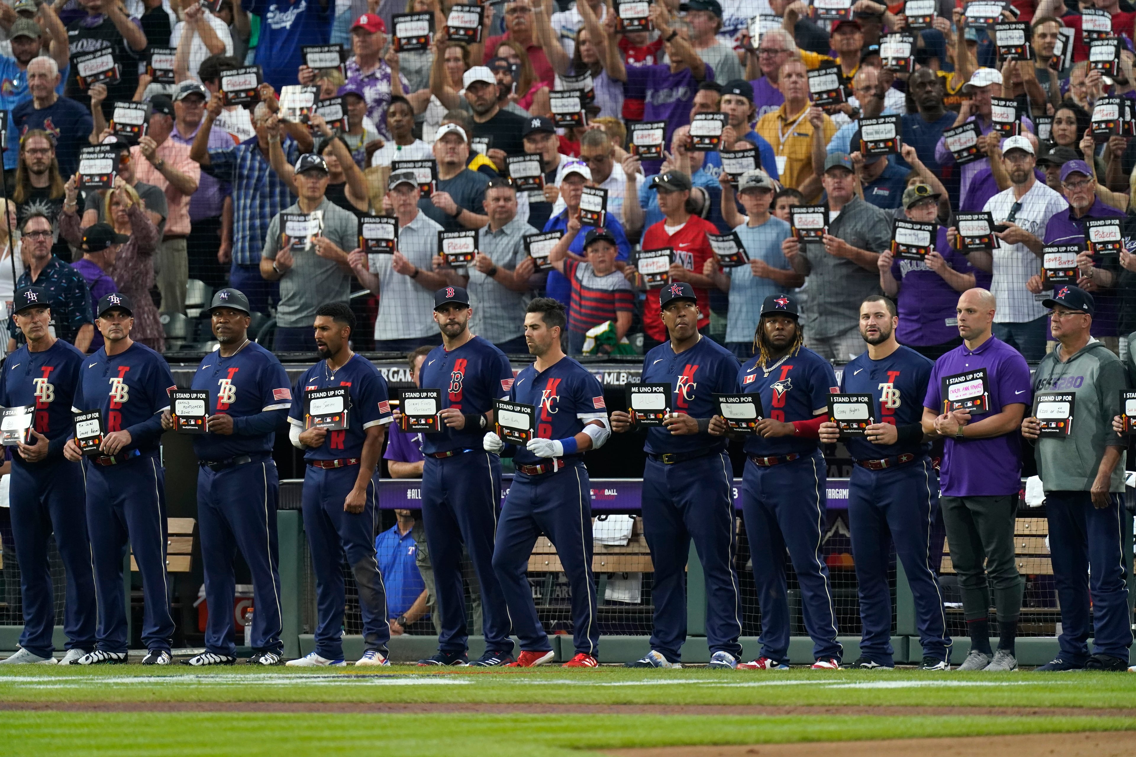 American League players hold signs for cancer awareness during the fifth inning of the MLB All-Star baseball game, Tuesday, July 13, 2021, in Denver. (AP Photo/Gabriel Christus)