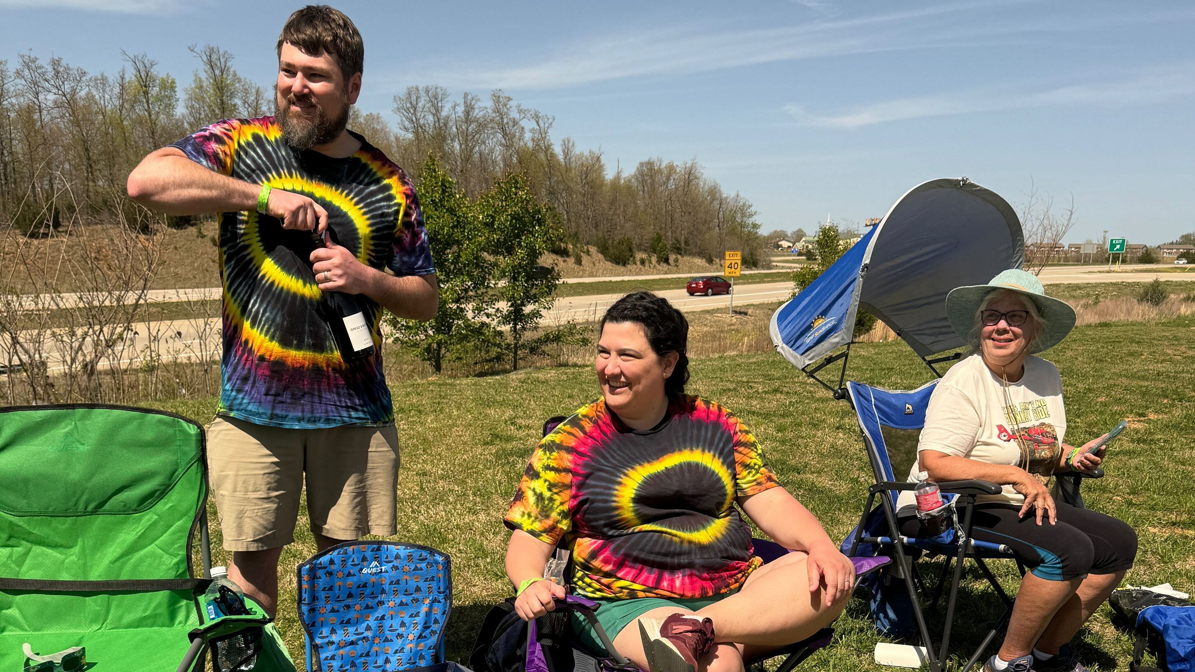 Matt Huggins, left, of Marietta, opens a bottle of wine to celebrate Monday’s total eclipse in Poplar Bluff, Missouri. His wife Katie, and mother-in-law Laura Stokes are seated next to him. (Charles Minshew / AJC)