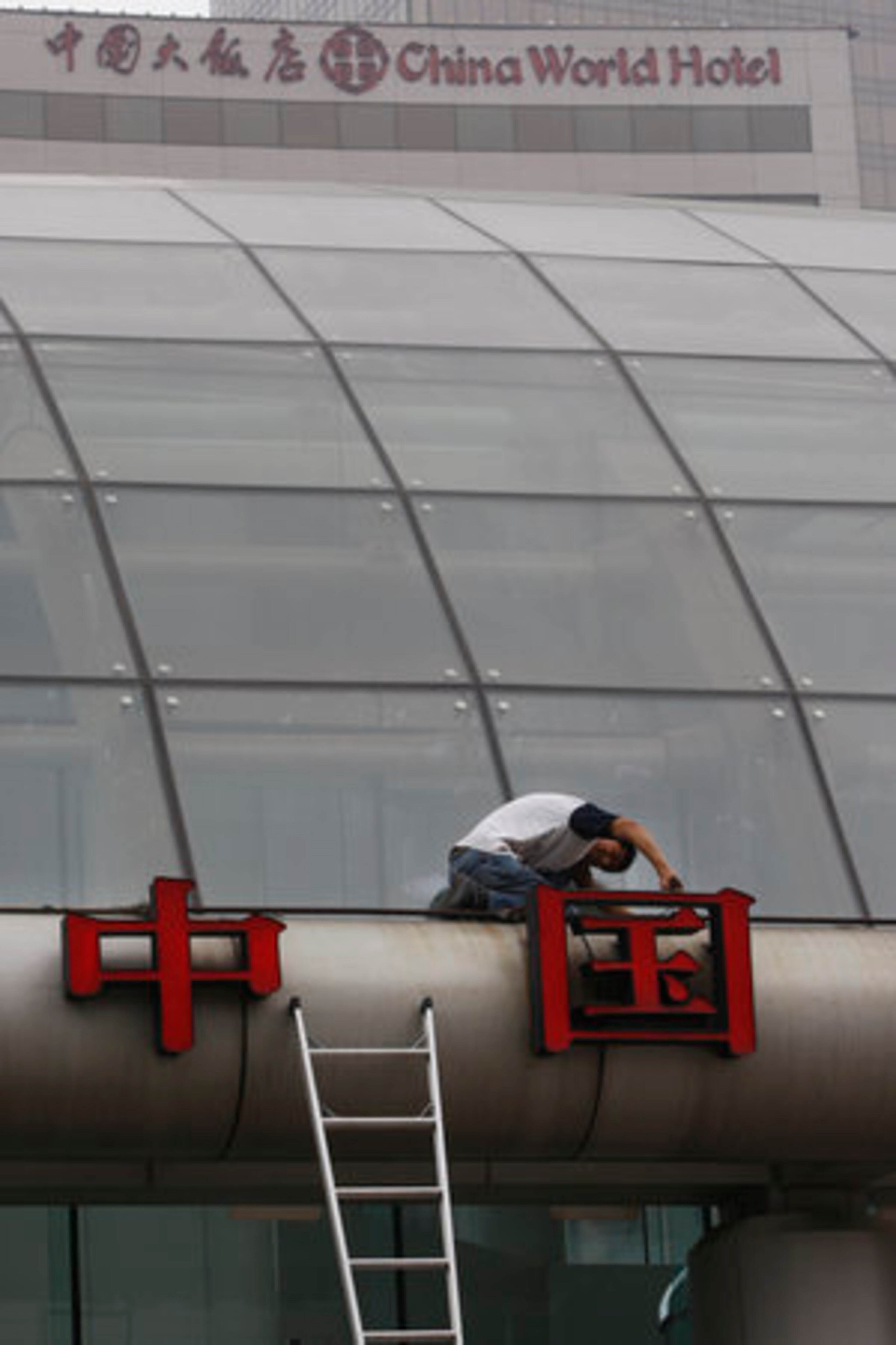 A worker checks the characters for the word "China" near the China World Hotel in Beijing on Thursday. The hotel says only about half its rooms are occupied now, in what is usually a busy travel time, while the perception of high prices and scarce tickets for the August Olympics is keeping visitors away.