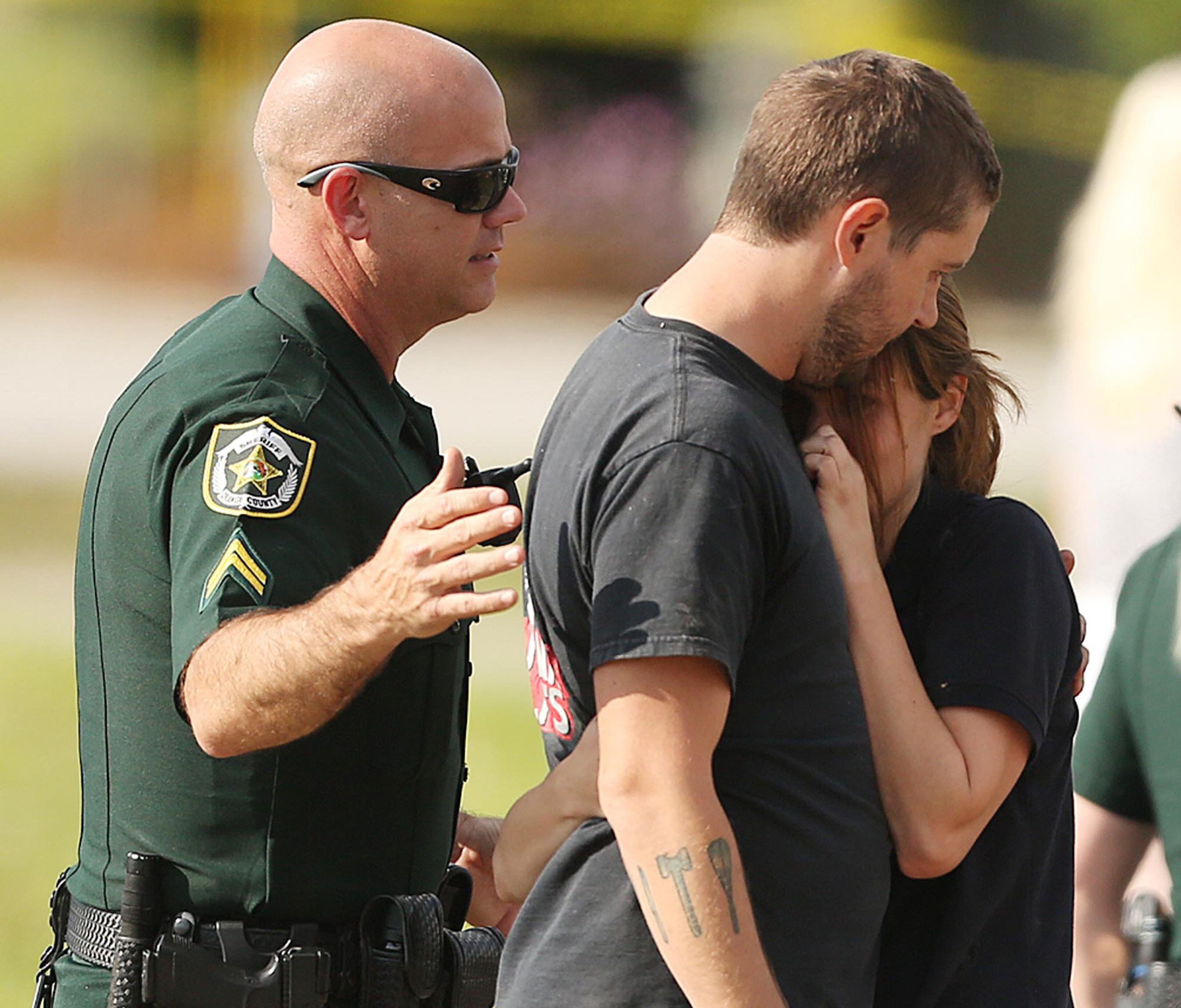 A couple is consoled by an officer after several children were injured when a car crashed into KinderCare Learning Center on Wednesday, April 9, 2014, in Winter Park, Fla. (Stephen M. Dowell, Orlando Sentinel/MCT)