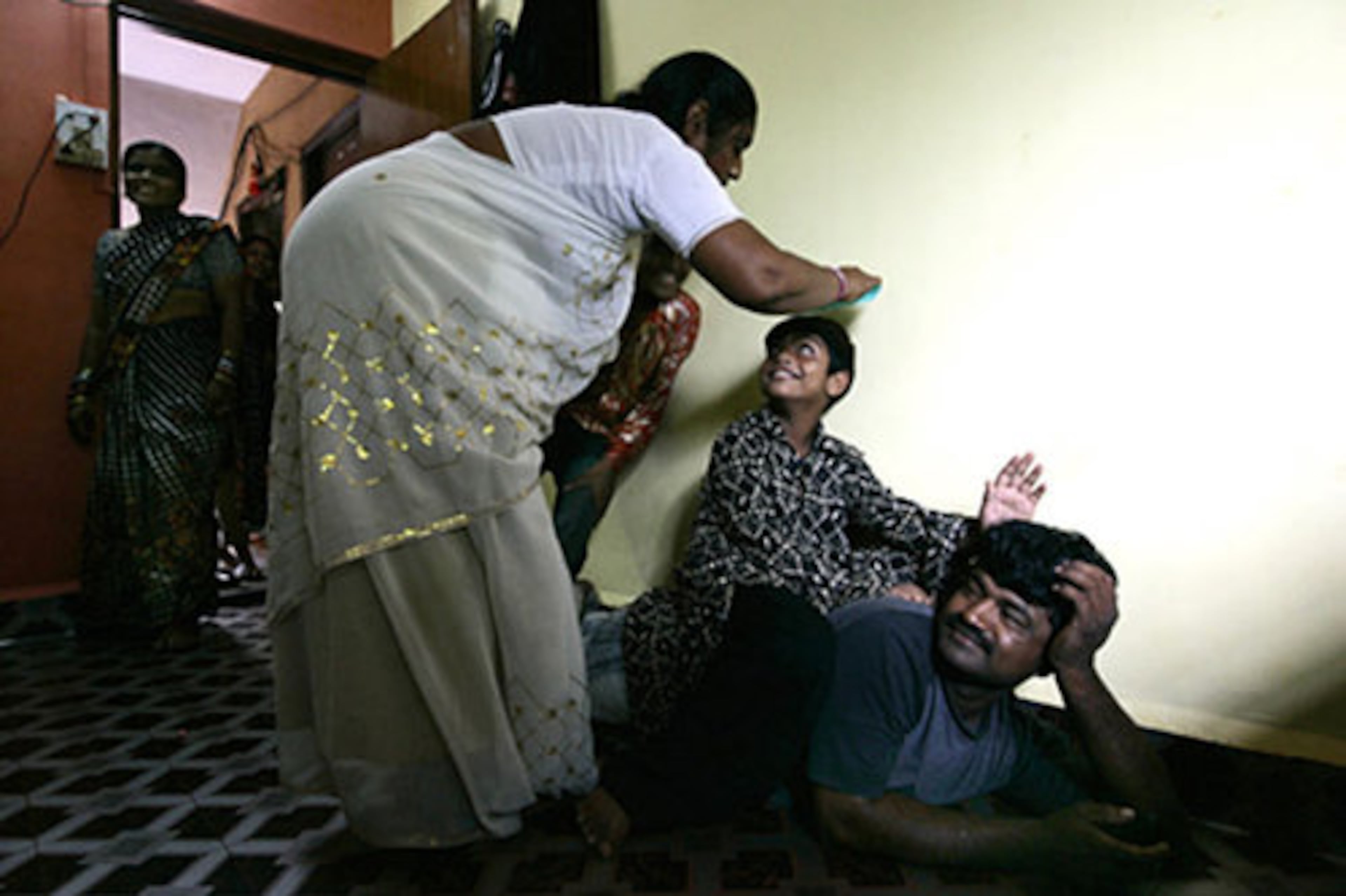 The mother of Azharuddin Mohammed Ismail combs his hair at their new home. They lost their home in May when authorities cleared part of a suburban Mumbai slum where they lived.