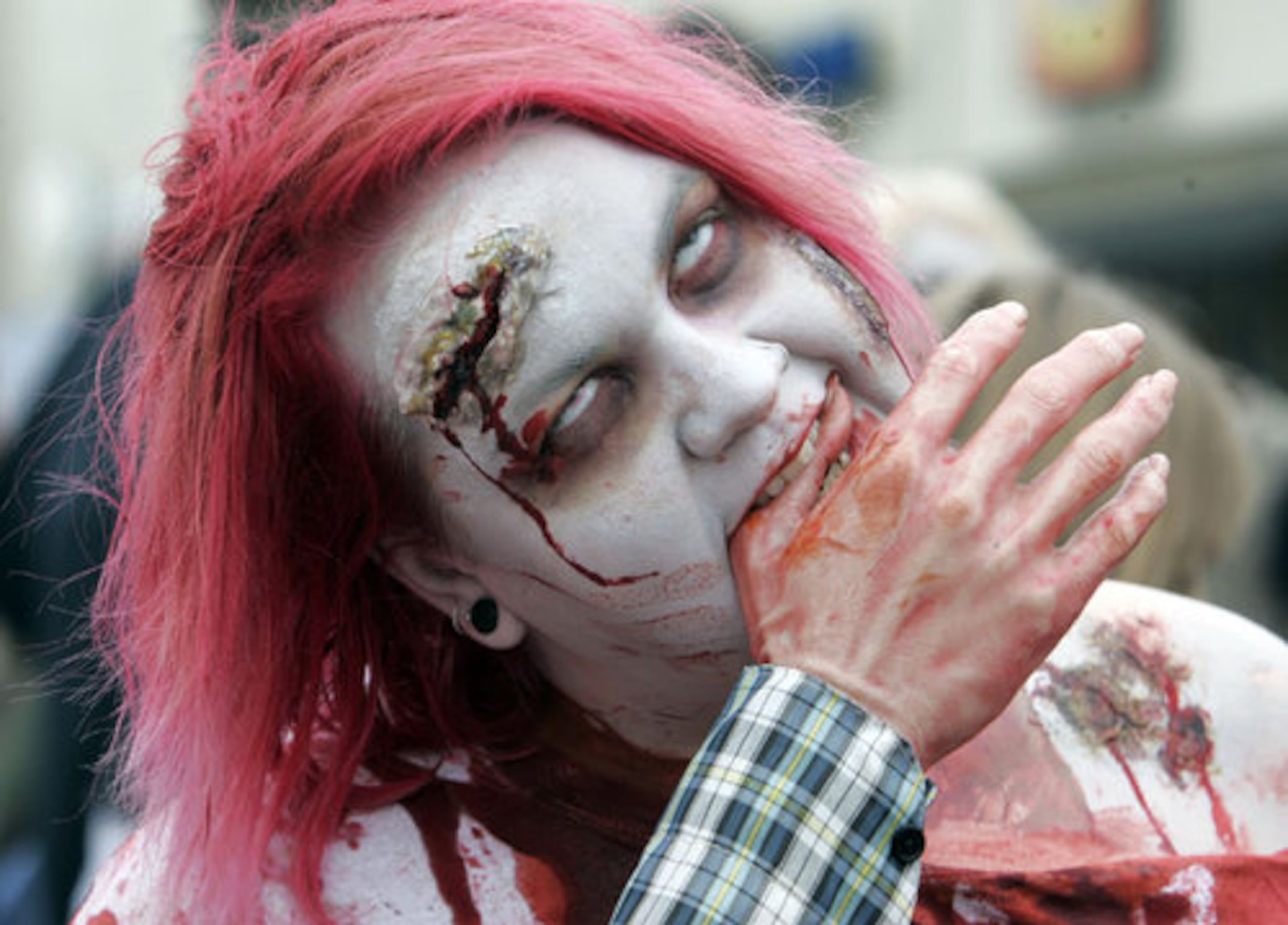 Heather Lewis, from Ellenwood, bites down on a fake hand as hundreds of people, many in very elaborate costumes, participate in the fourth annual Zombie Walk in Midtown Atlanta.
