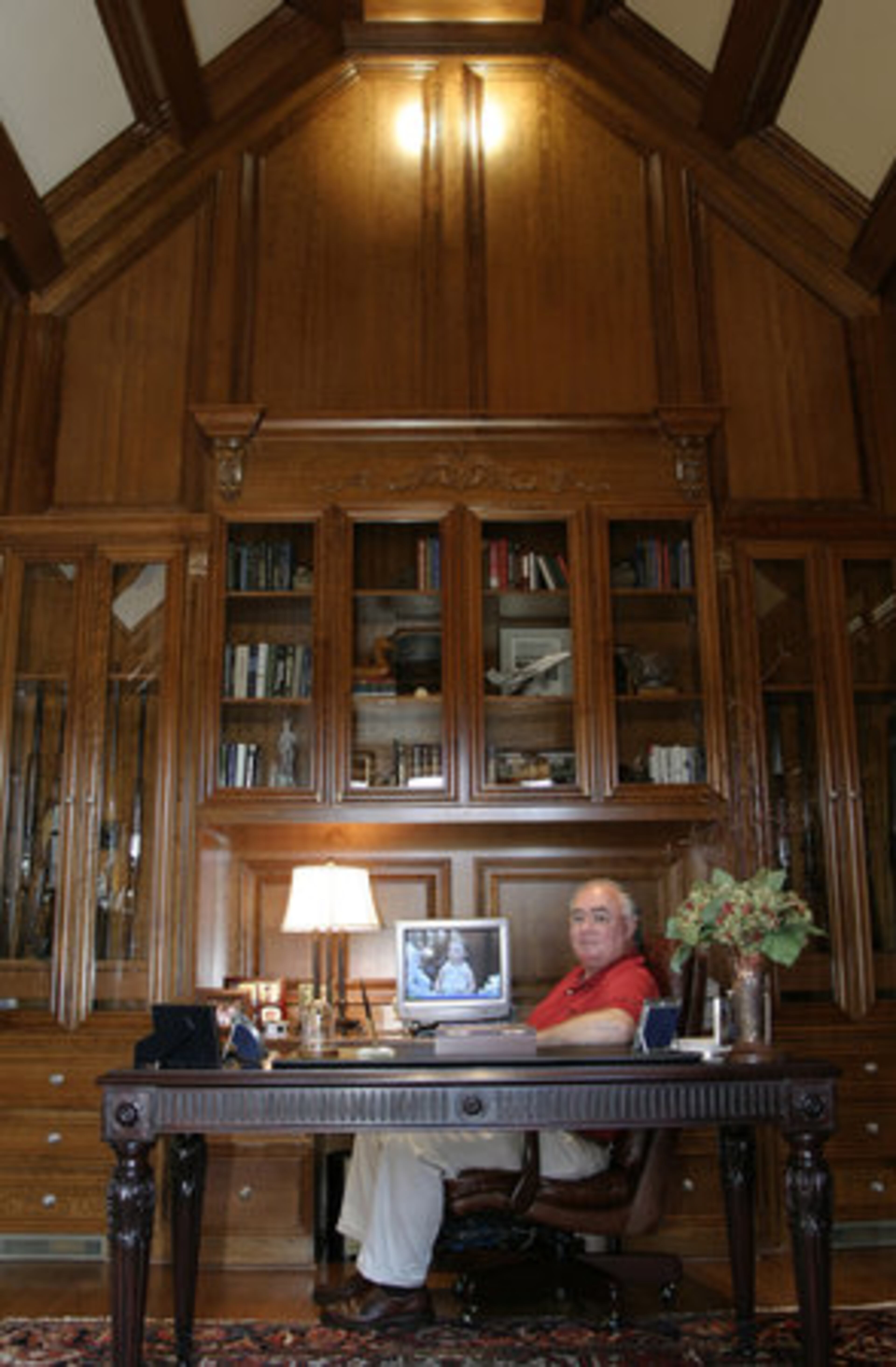 Gaylord Coan is proud of this cherry-paneled home office featuring steep ceilings and heavy beams. His computer workstation is flanked by his rifle collection. A trumpet-shaped fixture adds to the hunting motif, playing off Gaylord's interest in quail hunting.