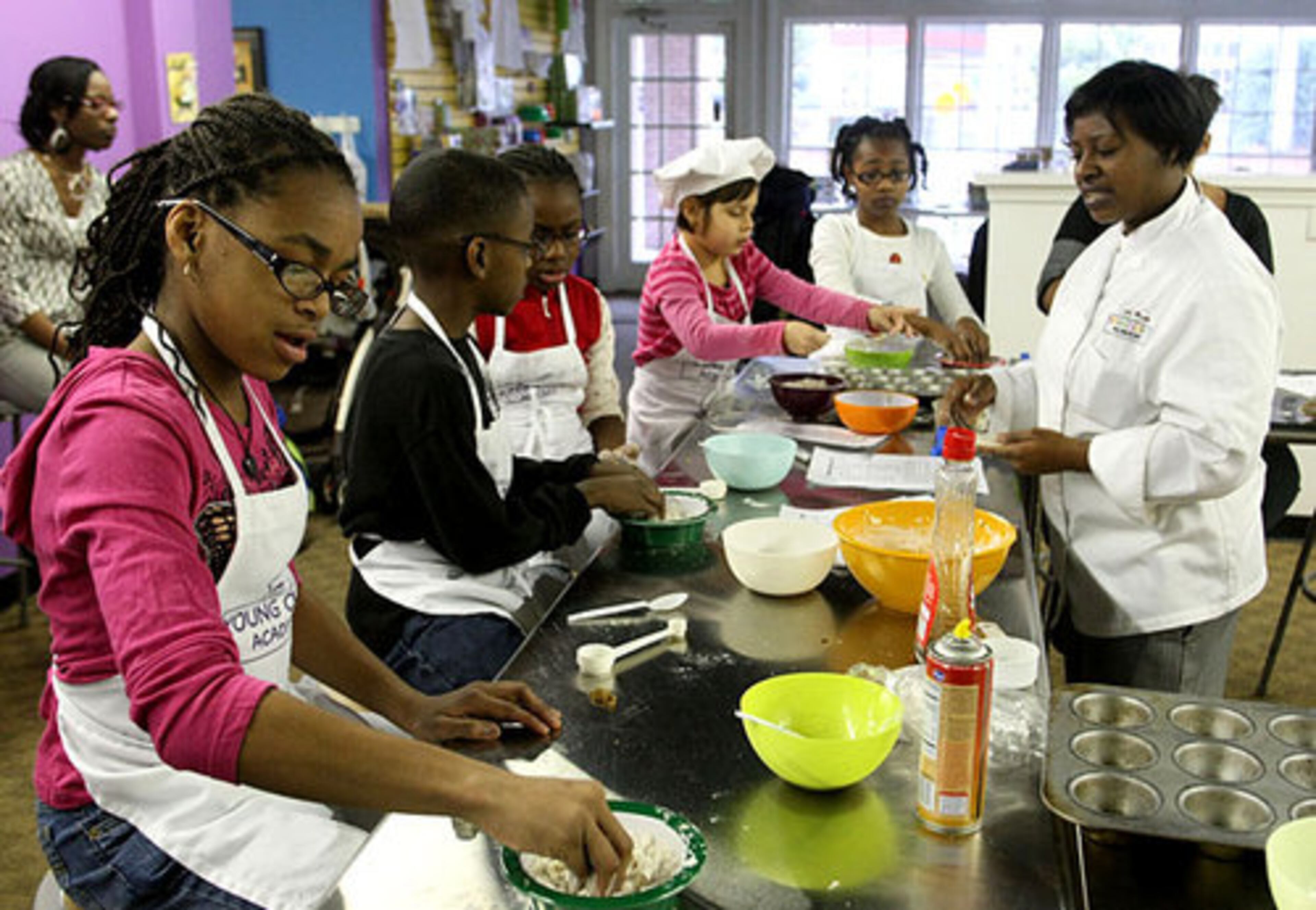 Twelve-year-old Kierra Winfrey, far left, adds flour to her Canadian Maple Sugar Pie during instructor Dene Lynn's, far right, cooking class.