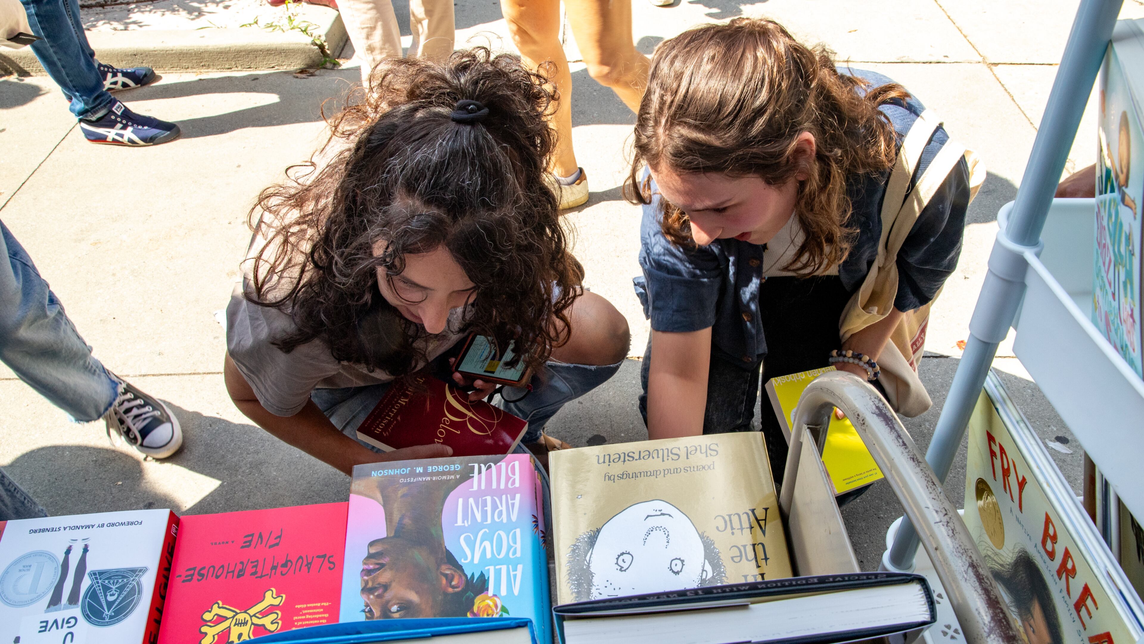 MoveOn Political Action's Banned Bookmobile distributes free banned books at the kickoff of National Banned Book Week where Shereen Mendelson (left) and Isabella Lipham take a look at a few of the banned books that cannot be checked out at public school libraries on Oct. 1, 2023, at Little Shop of Stories in Decatur Square. (Jenni Girtman for the AJC)