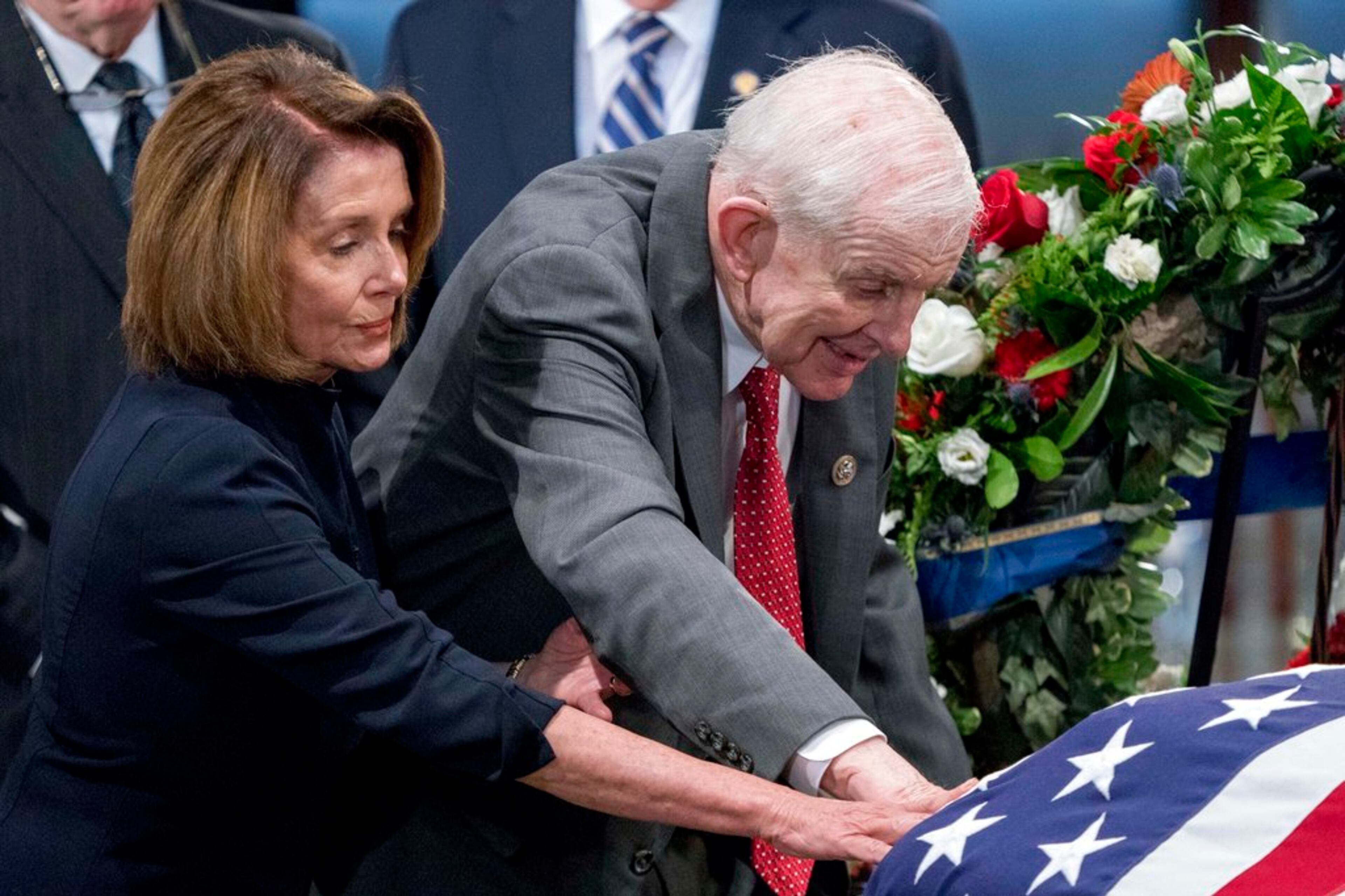 House Minority Leader Nancy Pelosi of Calif., left, and Rep. Sam Johnson, R-Texas, right, touch the casket of Sen. John McCain, R-Ariz., as he lies in state in the Rotunda of the U.S. Capitol, Friday, Aug. 31, 2018, in Washington. (AP Photo/Andrew Harnik, Pool)