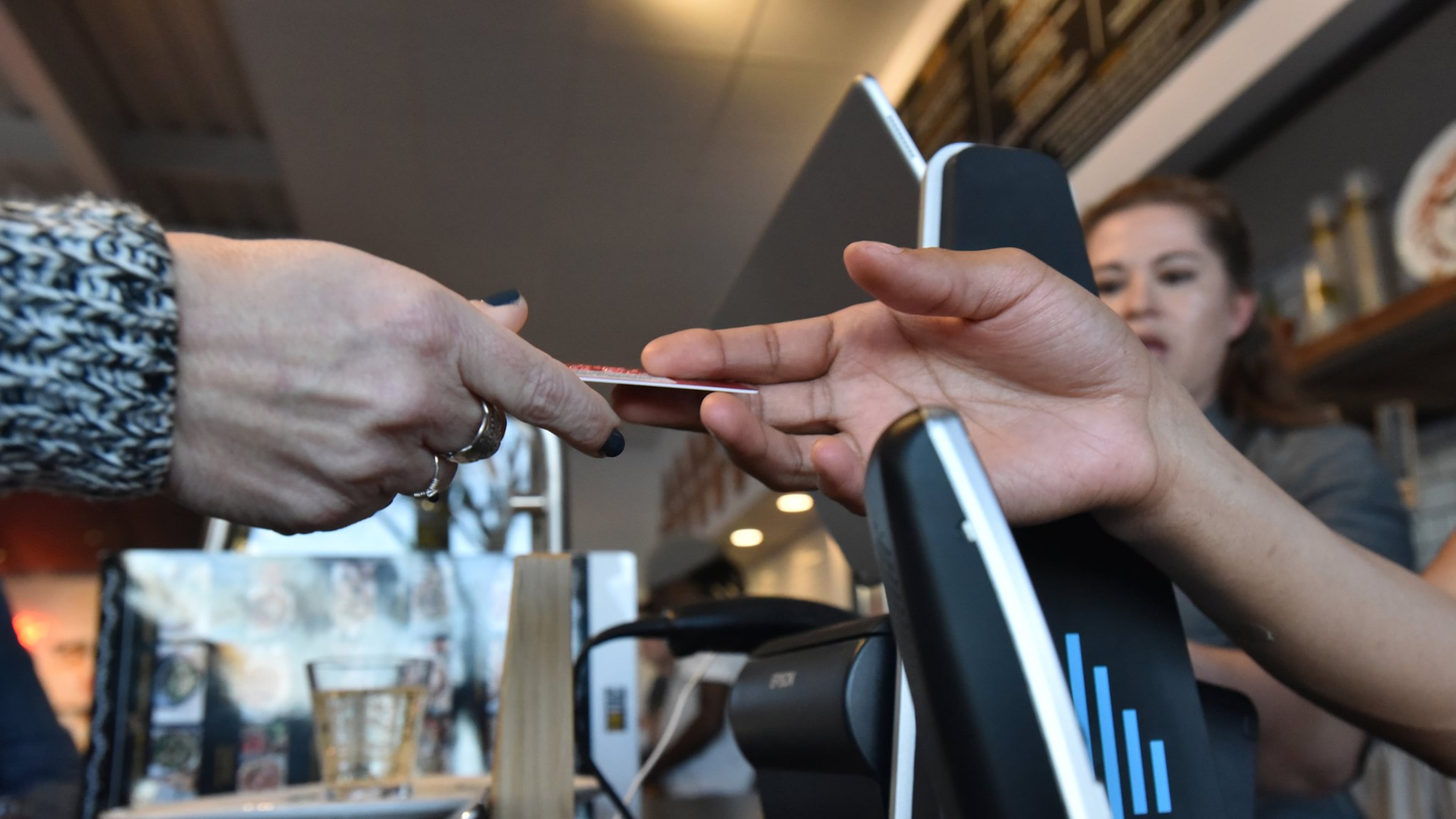 Pam Redman hands over her credit card to staffer Daylynn Brown at The Local Pizzaiolo in Atlanta. The restaurant is one of several in the area that don’t accept cash. HYOSUB SHIN / HSHIN@AJC.COM