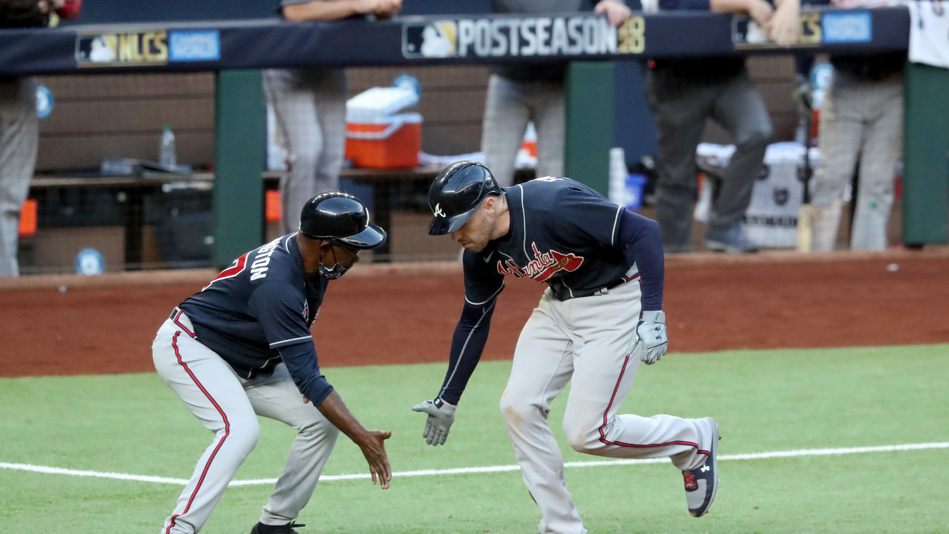 The Braves' Freddie Freeman, right, celebrates his two-run home run with third base coach Ron Washington against the Los Angeles Dodgers during the fourth inning in Game 2 of the National League Championship Series at Globe Life Field in Arlington, Texas, on Tuesday. (Curtis Compton/Atlanta Journal-Constitution/TNS)