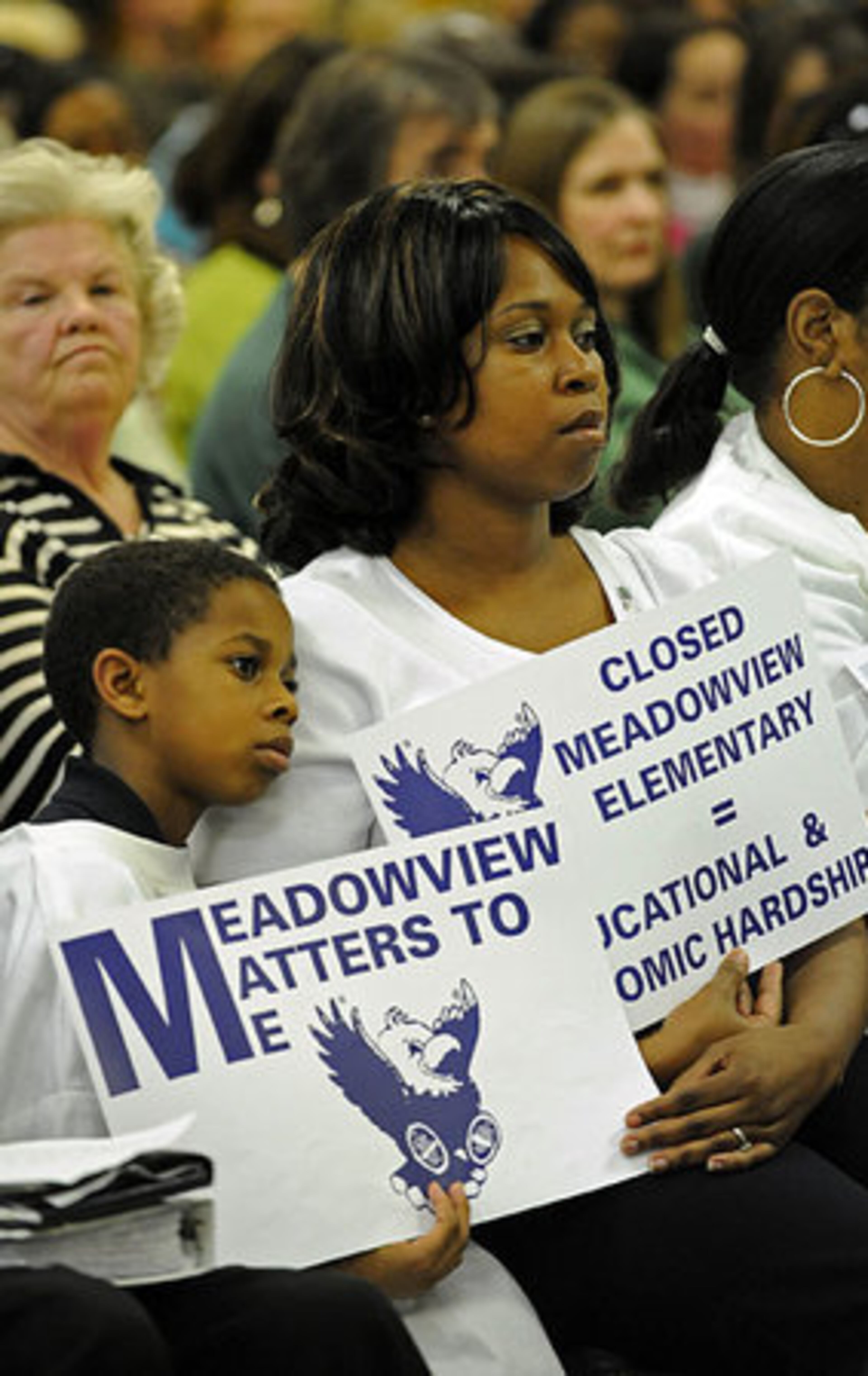 Ronda Ward and her 7 year-old son William Bradley, who is a 1st grader at Meadowview Elementary School, hold signs to support their school during the Citizens' Planning Task Force meeting Tuesday night at William Bradley Bryant Center in Decatur.