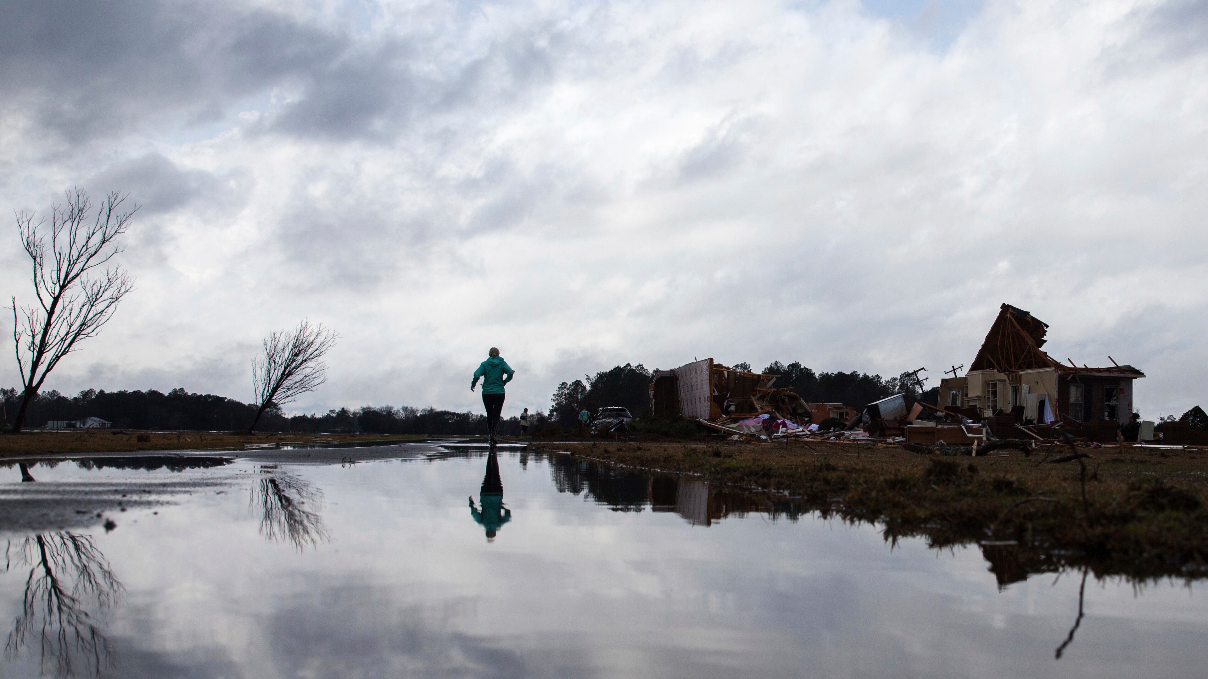 Marilyn Bullard makes her way to a home that was damaged by a tornado, Sunday, Jan. 22, 2017, in Adel, Ga. (AP Photo/Branden Camp)