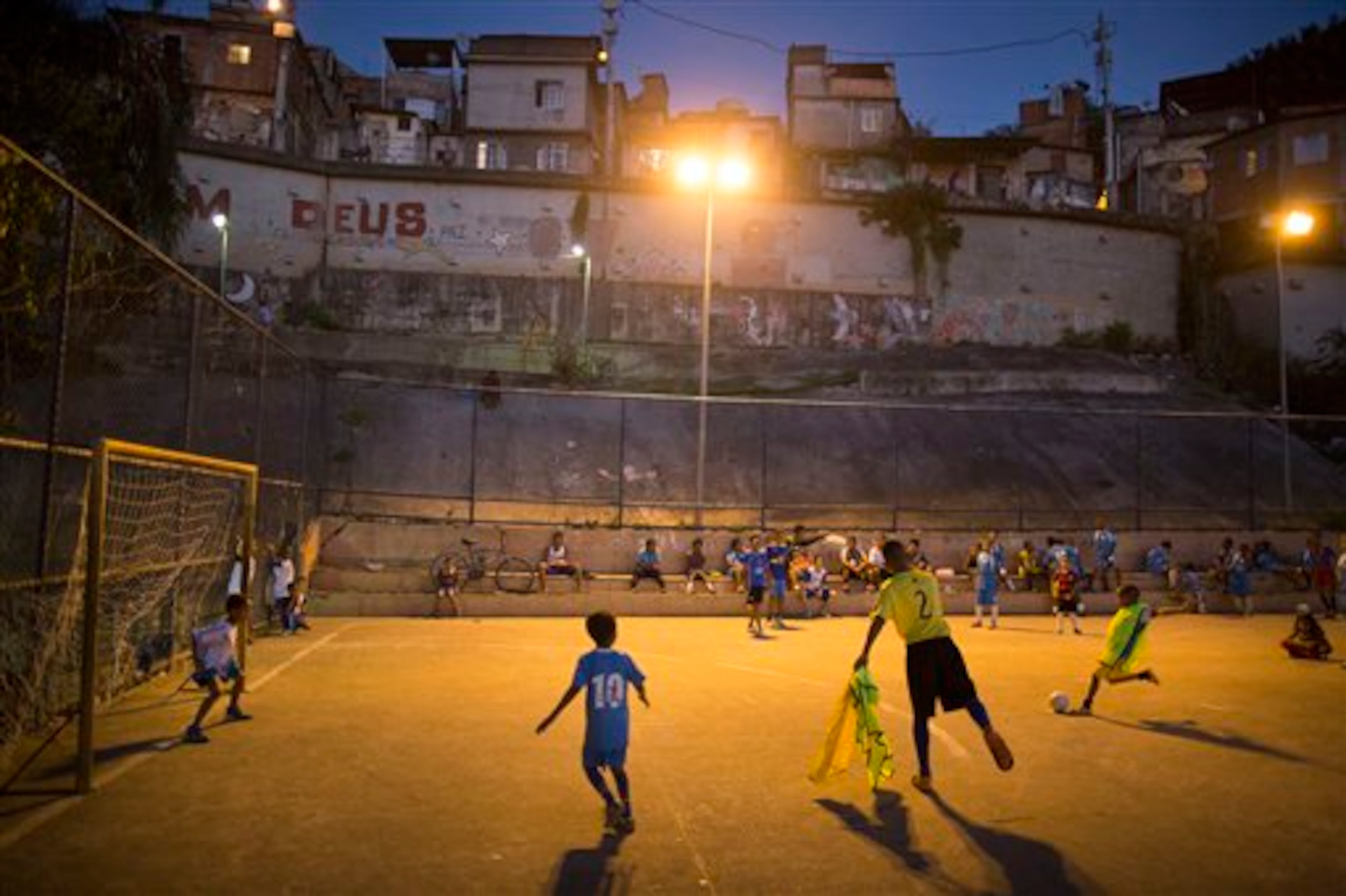 In this Monday, June 2, 2014 photo, children attend a soccer school class on a court in the Mangueira slum of Rio de Janeiro, Brazil. The aspiring soccer stars of Rio de Janeiro's historic Mangueira slum don't have far to look for inspiration. The slum sits on a hill overlooking Brazil's temple to soccer, the fabled Maracana stadium, where legends from Pele to Neymar have played. (AP Photo/Leo Correa)