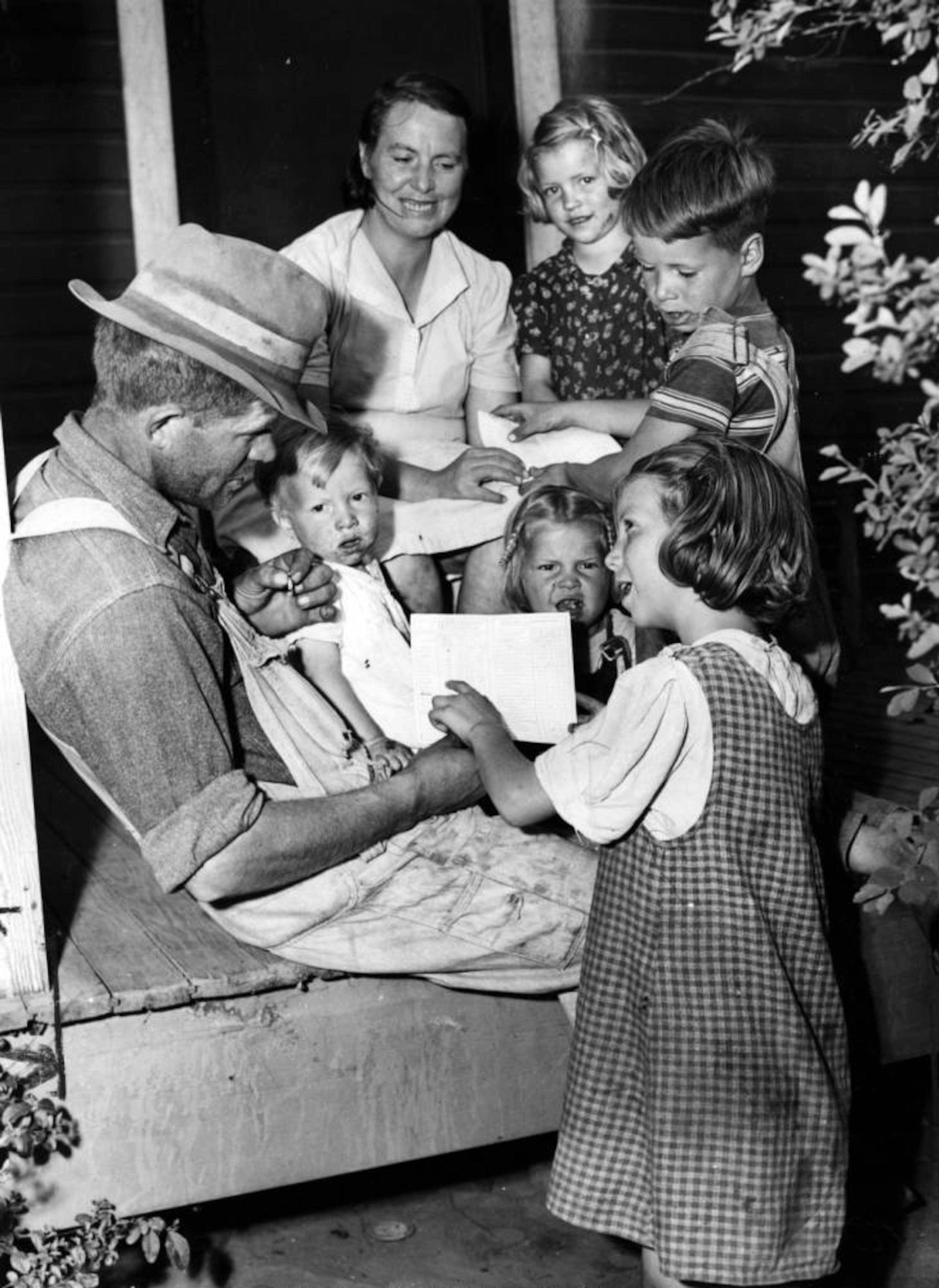 Dan McDowell's family, a farm family, look at Wynona's report card, Georgia mountains, ca. 1930s; 1940s..