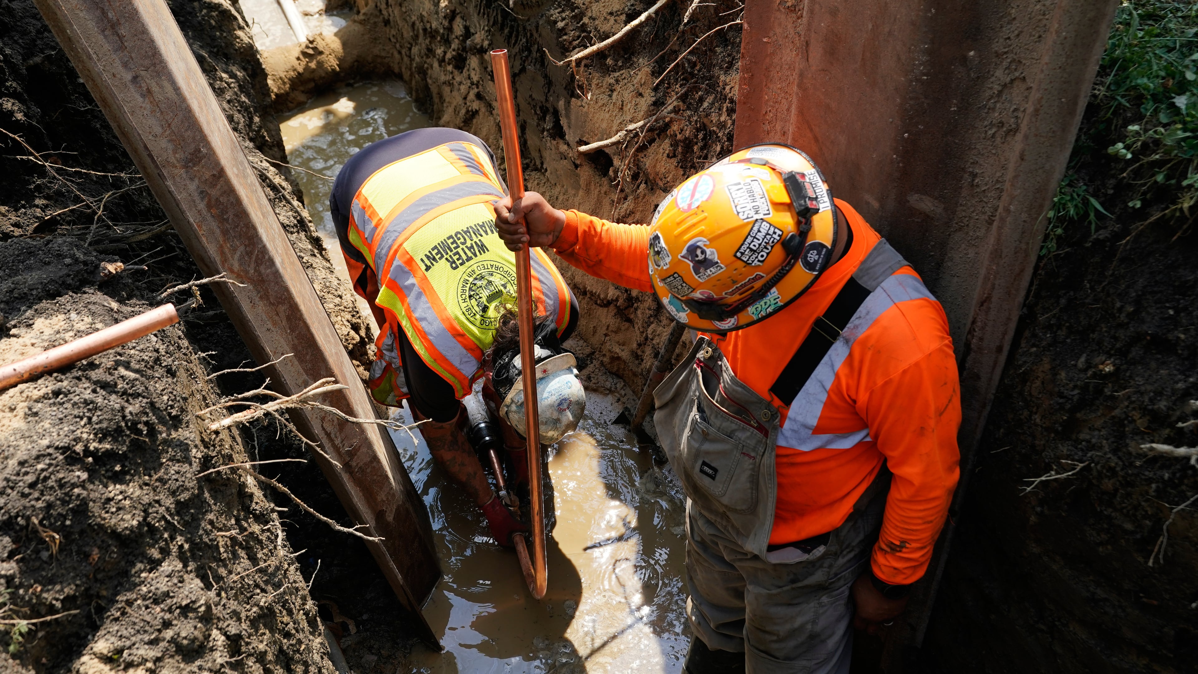 Workers install a copper pipe to replace a lead service line that brings drinking water to homes Tuesday, July 21, 2026, in Chicago. (AP Photo/Alyssa Goodman)