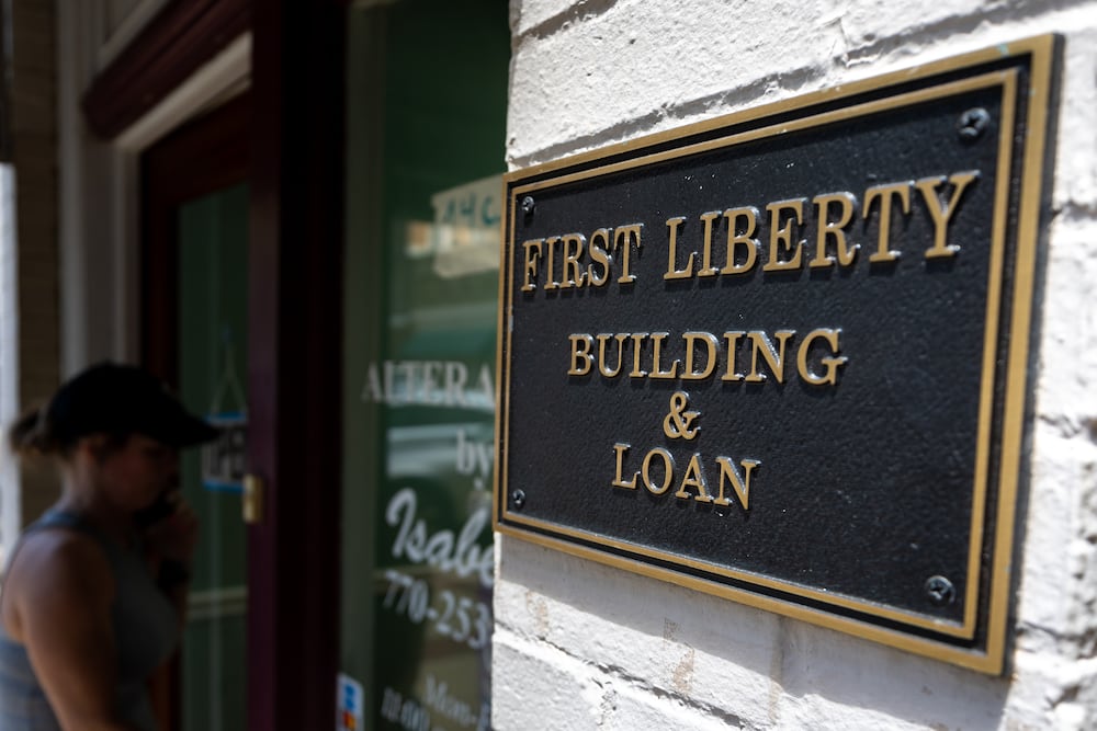 A person walks into the store next to First Liberty Building & Loan in downtown Newnan last July. (Arvin Temkar/AJC)