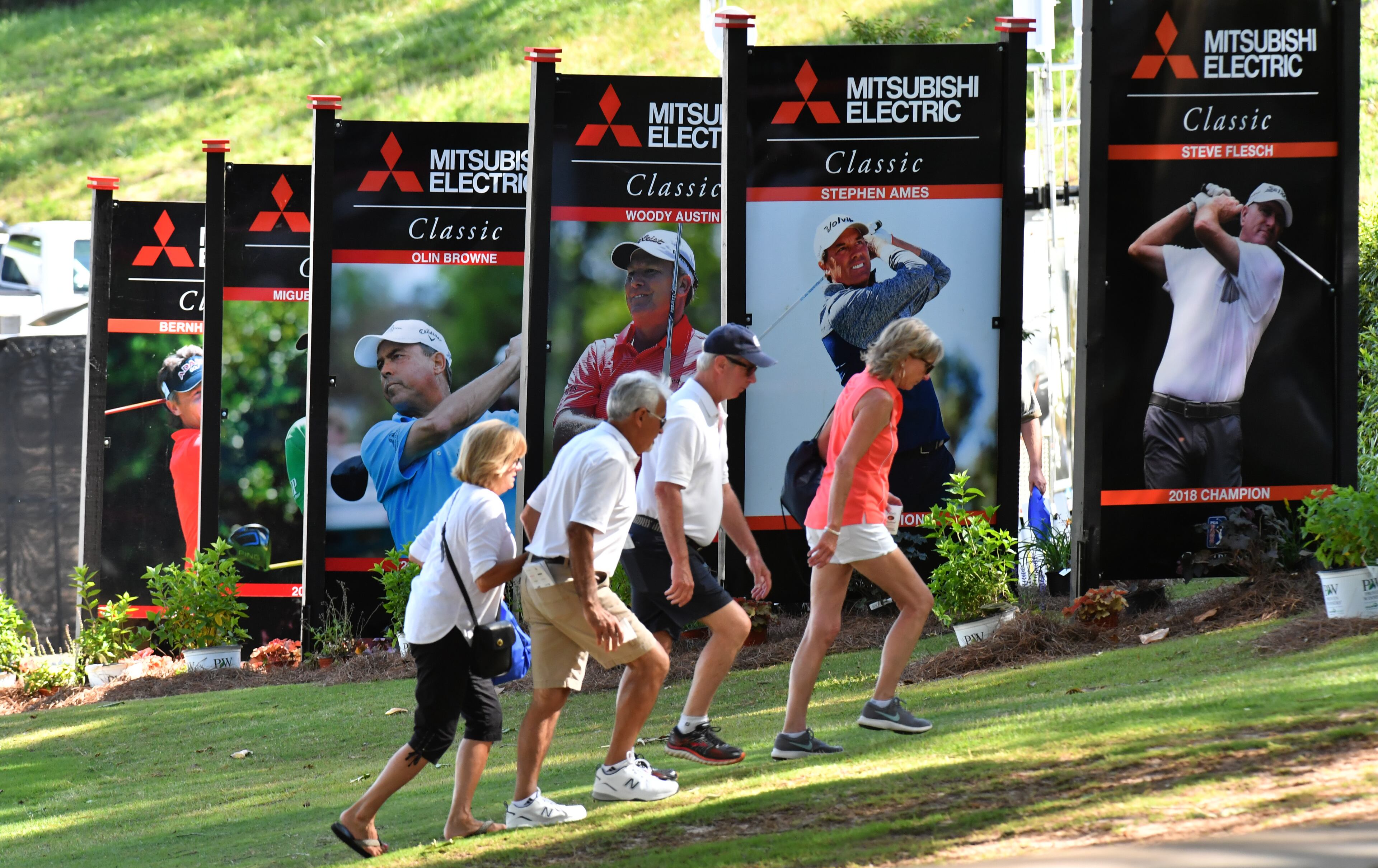Spectators walk past banners during the first round of the Mitsubishi Electric Classic at TPC Sugarloaf on Friday, May 14, 2021. (Hyosub Shin / Hyosub.Shin@ajc.com)