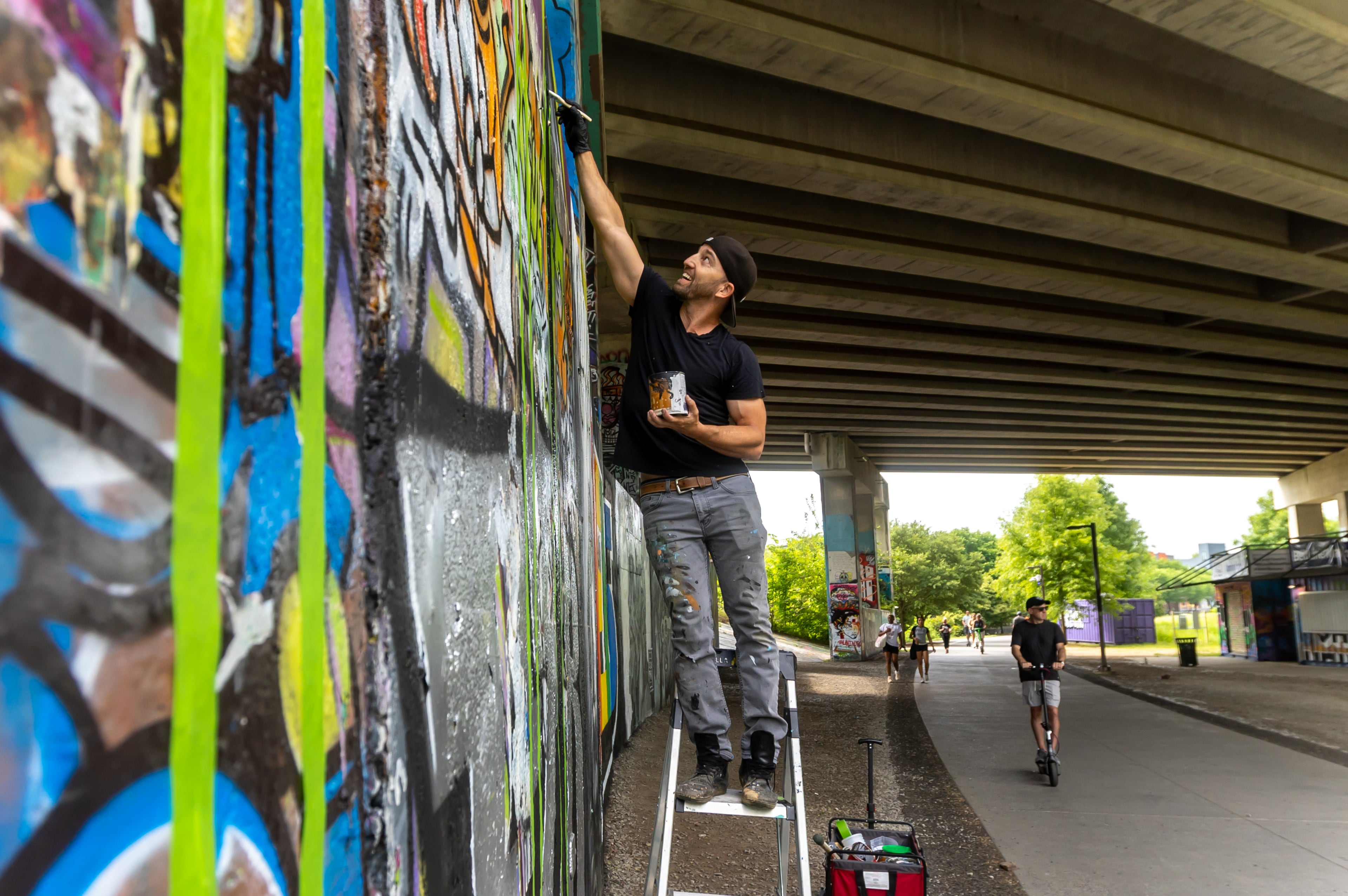 Artist DasBK paints a mural along the Beltline near the Historic Fourth Ward Skate Park. In recent years, the city of Atlanta has made meaningful commitments to parks funding, guest columnist Michael Halicki writes. (John Spink/AJC 2024)