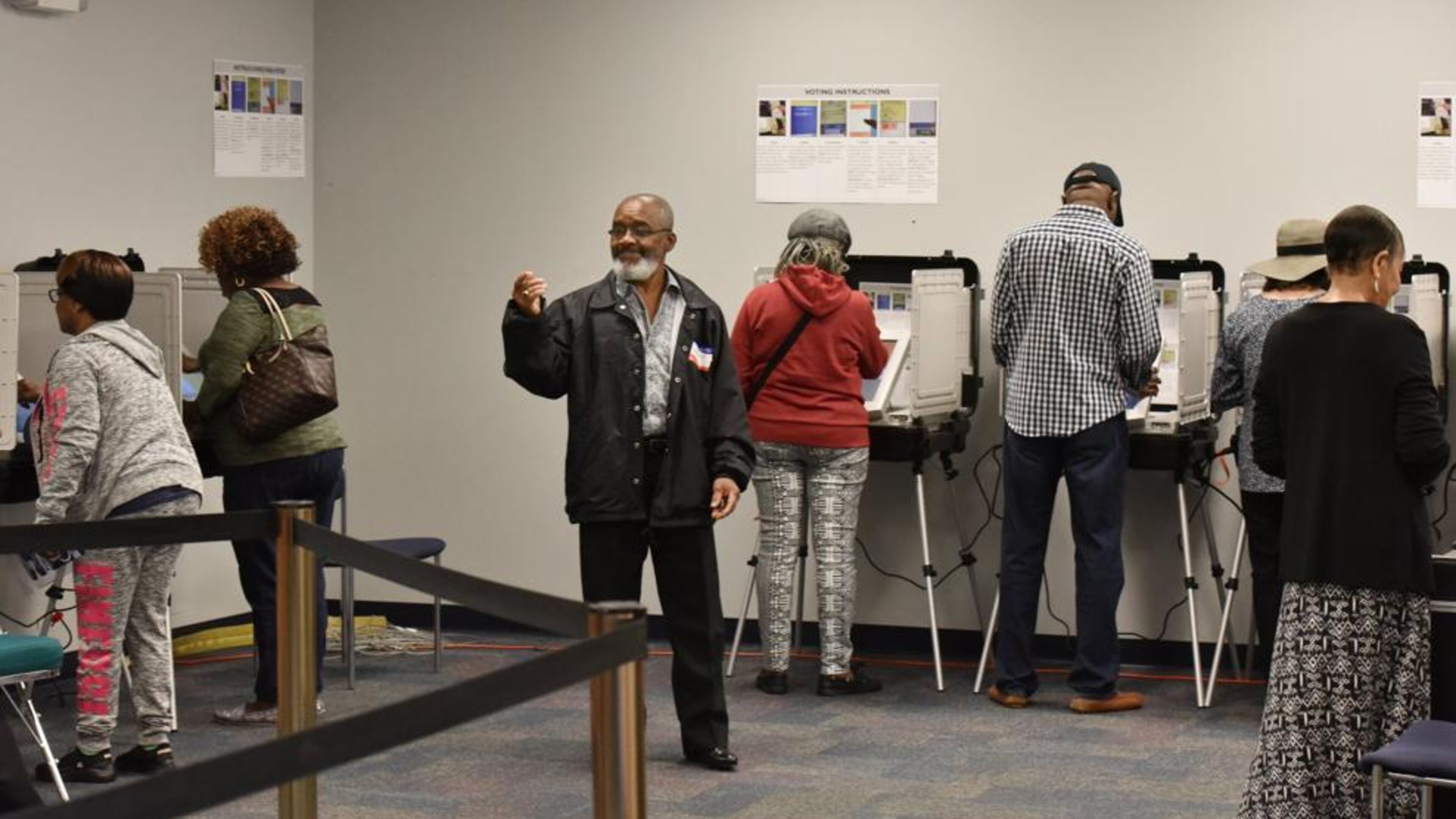 Volunteer Alfred Leblanc (center) directs early voters at the Gwinnett County Voter Registrations and Elections Office in Lawrenceville on Thursday, Oct. 18, 2018.