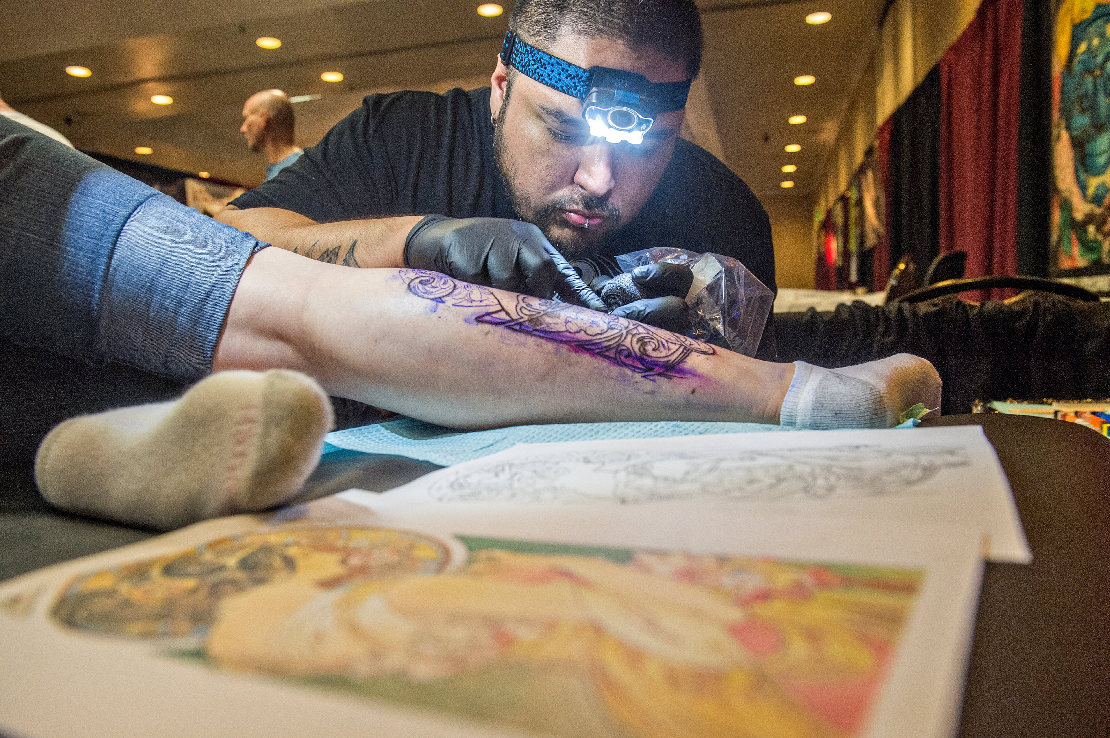June 20, 2015 Atlanta - Matthew Gasca (right) works on a leg tattoo for Pacie Jordan during the 19th annual Atlanta Tattoo Expo at the Wyndham Atlanta Galleria hotel on Saturday, June 20, 2015. Around 100 tattoo artists from across the country were booked solid throughout the three day event as hundreds of people came out to watch and get tattooed. JONATHAN PHILLIPS / SPECIAL