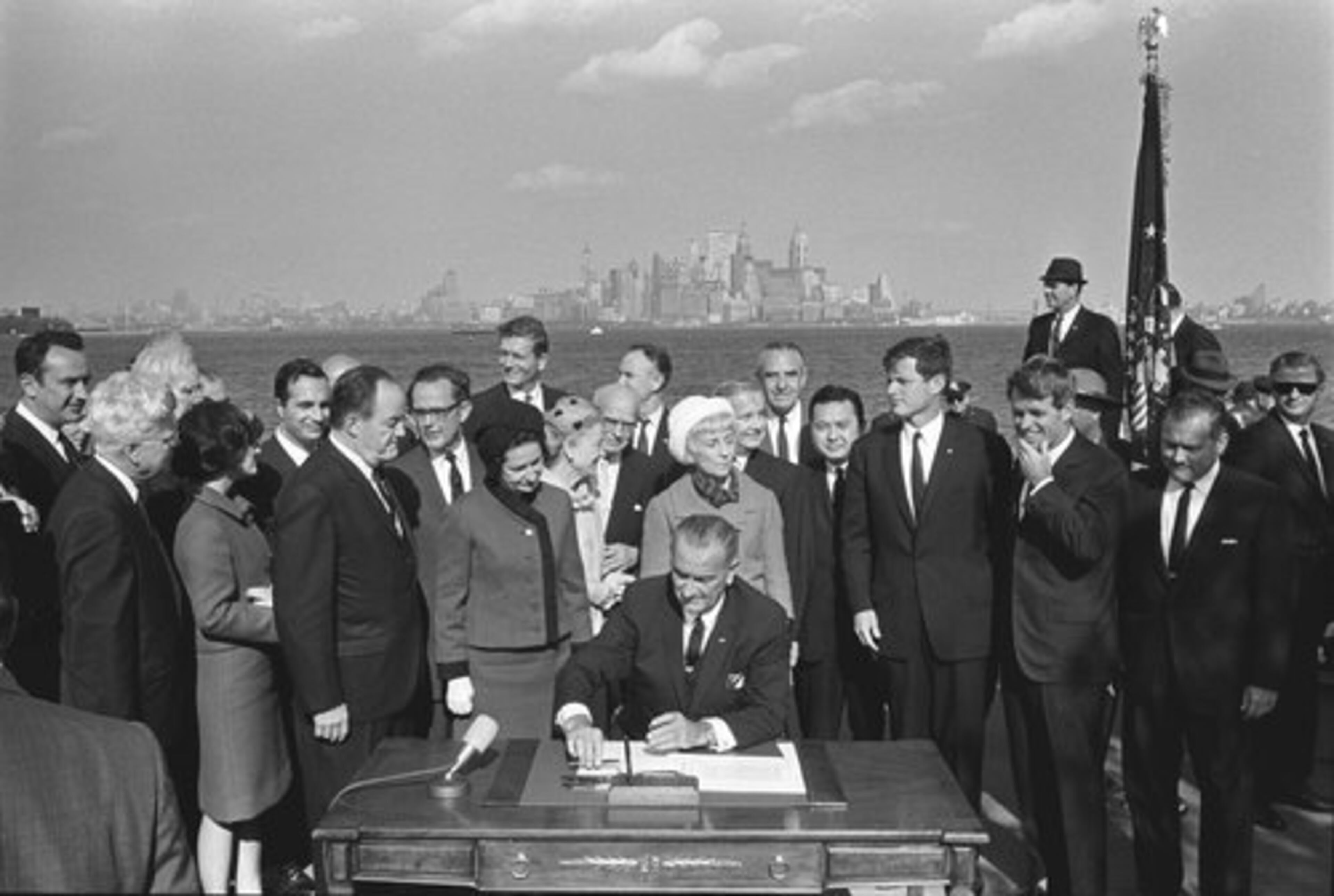 President Lyndon B. Johnson signs the Immigration Act, October 3, 1965. Joining Johnson at the signing are Sen. Edward Kennedy, center right, Robert Kennedy, right, and Vice President Hubert H. Humphrey.