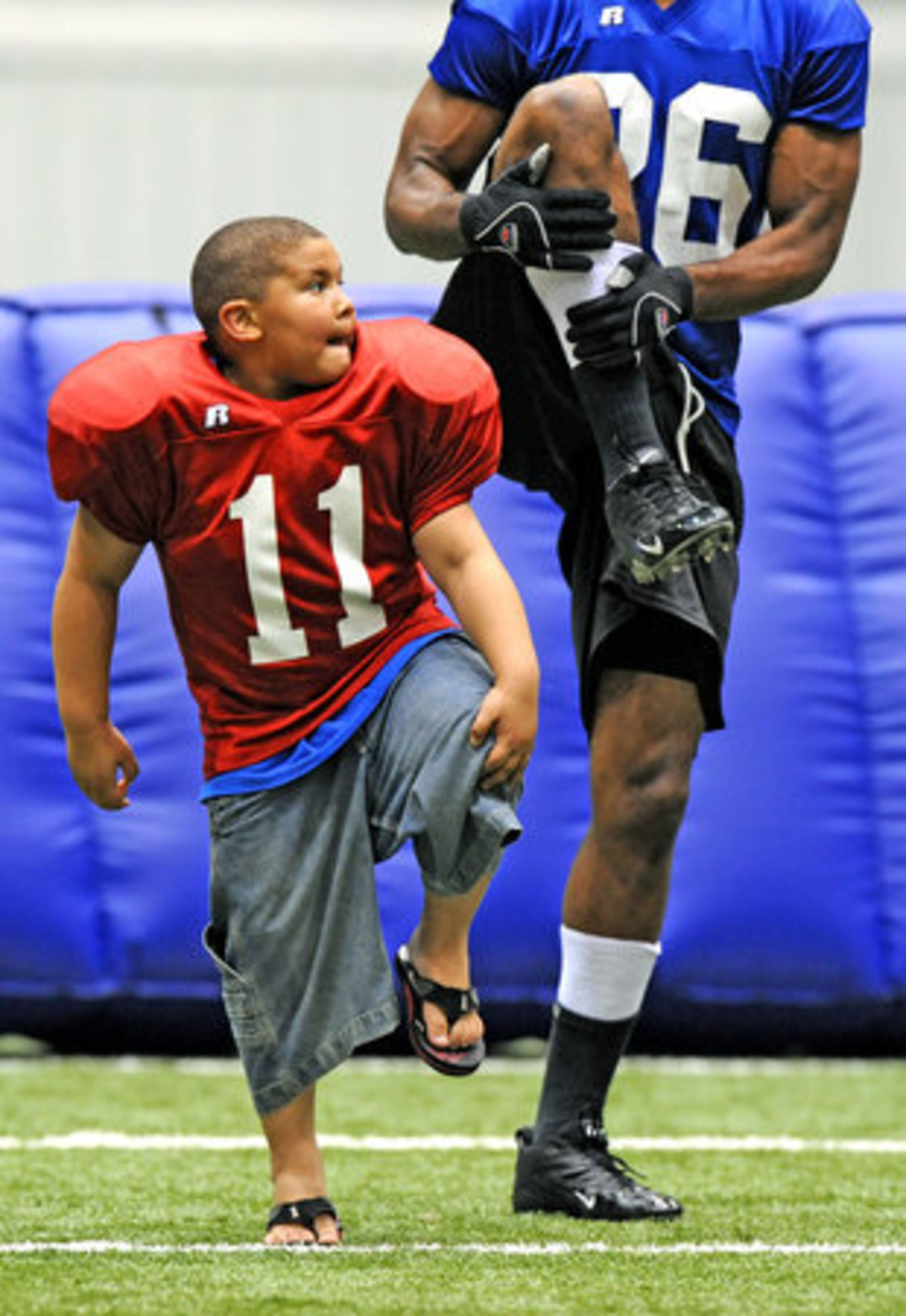 Javon Smith, 6, tries to keep in step with Georgia Force's Vernon Hugen during warm-up drills Friday morning at Flowery Branch. Smith's father, Jermaine Smith, is a defensive lineman with the Arena League team, which hosts a division playoff game at the Gwinnett Arena on July 7th.