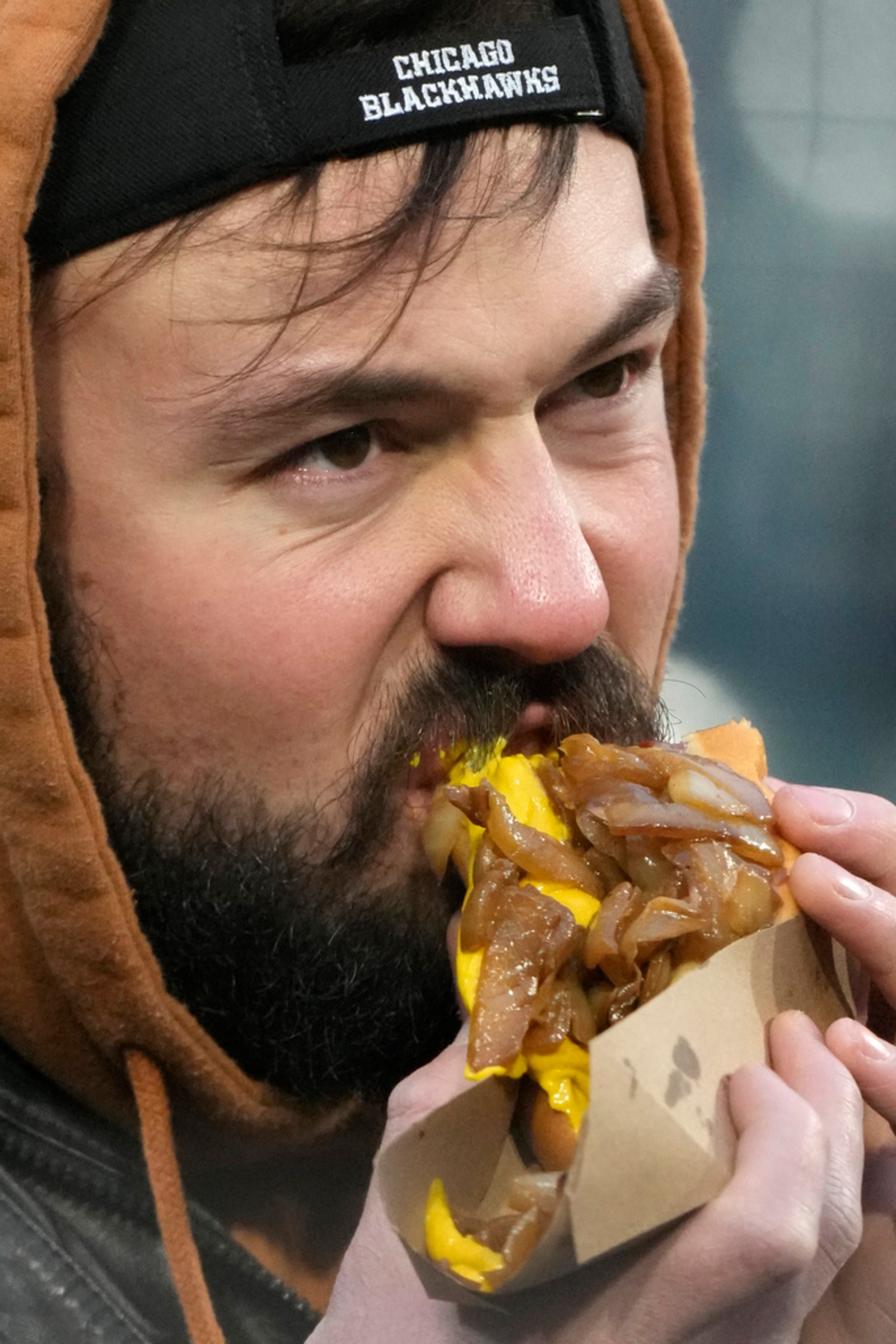 A fan eats a hot dog as he watches the first inning of a baseball game between the Atlanta Braves and the Chicago White Sox in Chicago, Tuesday, April 2, 2024. (AP Photo/Nam Y. Huh)