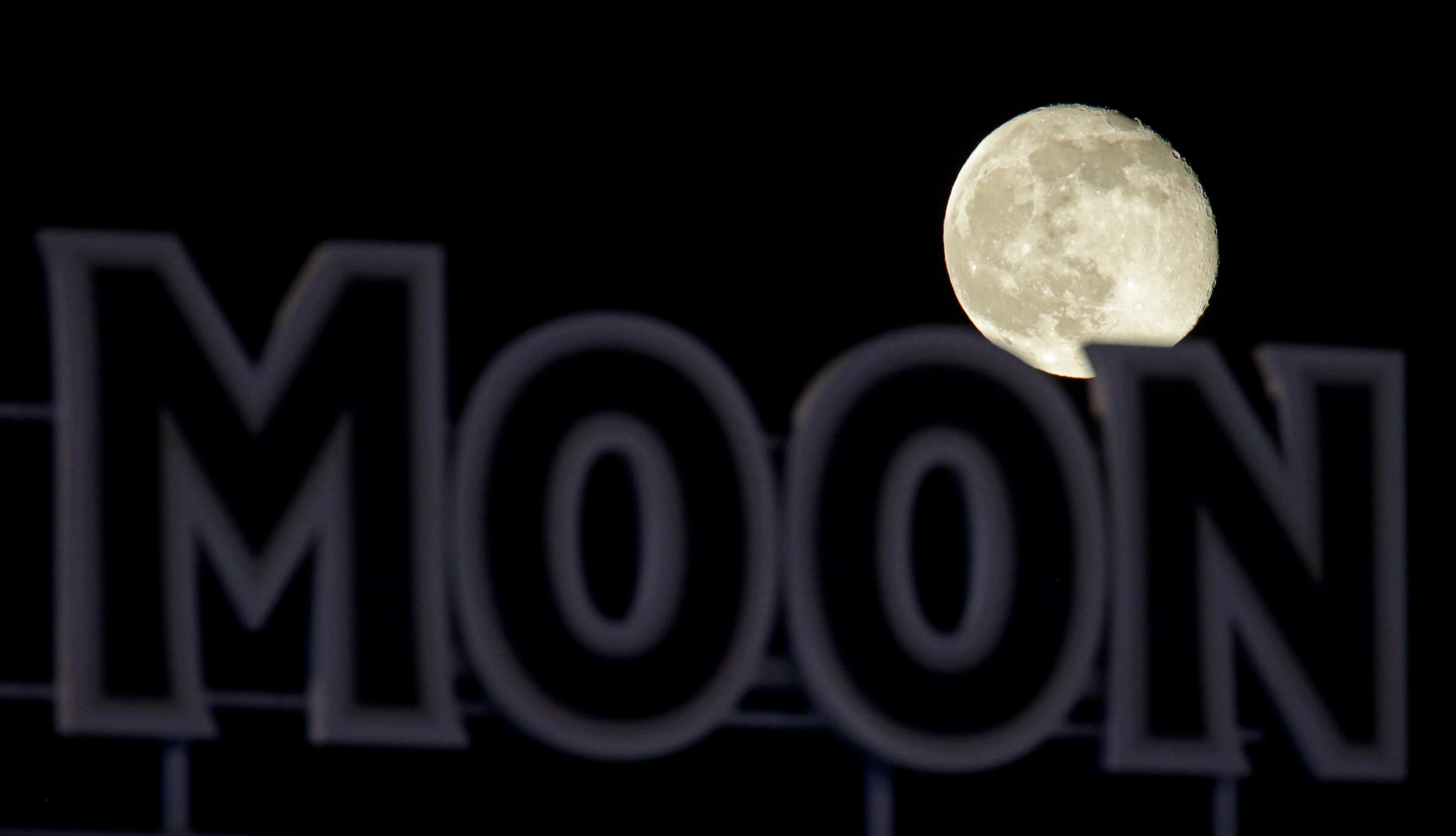 The waning full moon rises beyond a sign at Kauffman Stadium after a baseball game between the Kansas City Royals and the Baltimore Orioles Friday, May 12, 2017, in Kansas City, Mo. (AP Photo/Charlie Riedel)