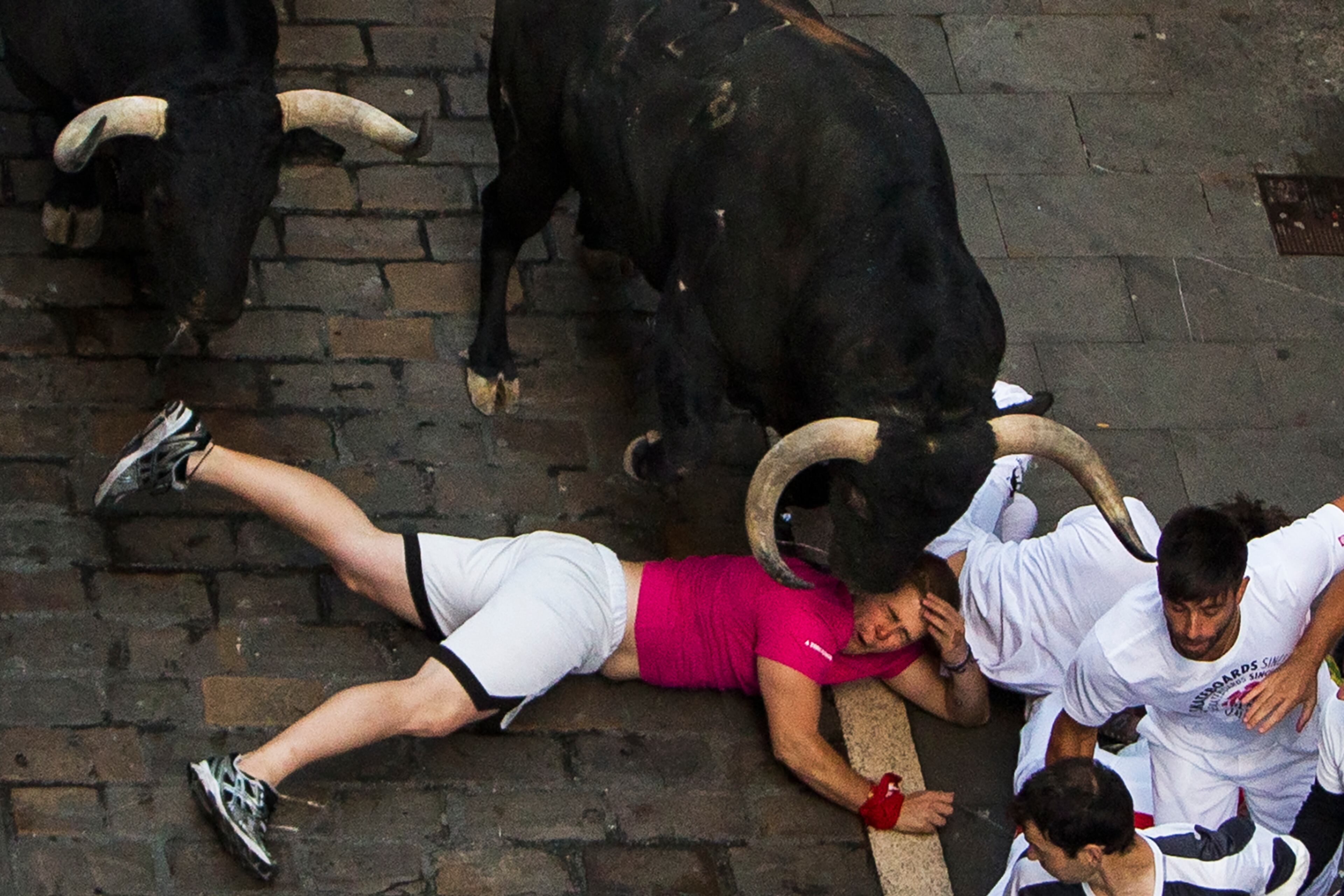 Victoriano del Rio fighting bulls run over revelers during the running of the bulls, at the San Fermin festival, in Pamplona, Spain, Thursday, July 9, 2015. Revelers from around the world arrive in Pamplona every year to take part in some of the eight days of the running of the bulls. (AP Photo/Andres Kudacki)