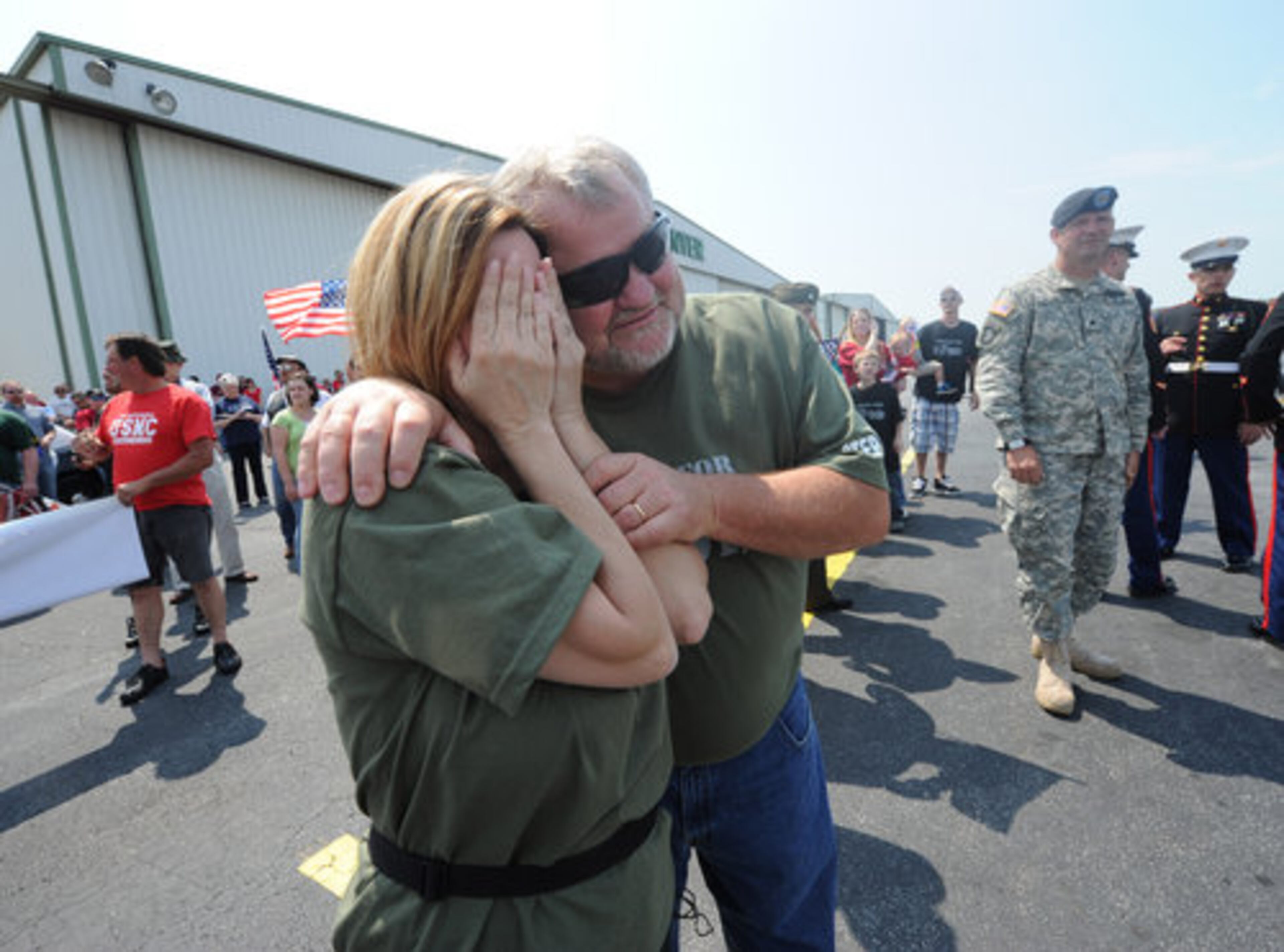 Jimmy Cox holds his wife Tammy Cox as she spots the plane bringing home her son Marine Cpl. Todd Simpson Love to McCollum Field on Saturday.