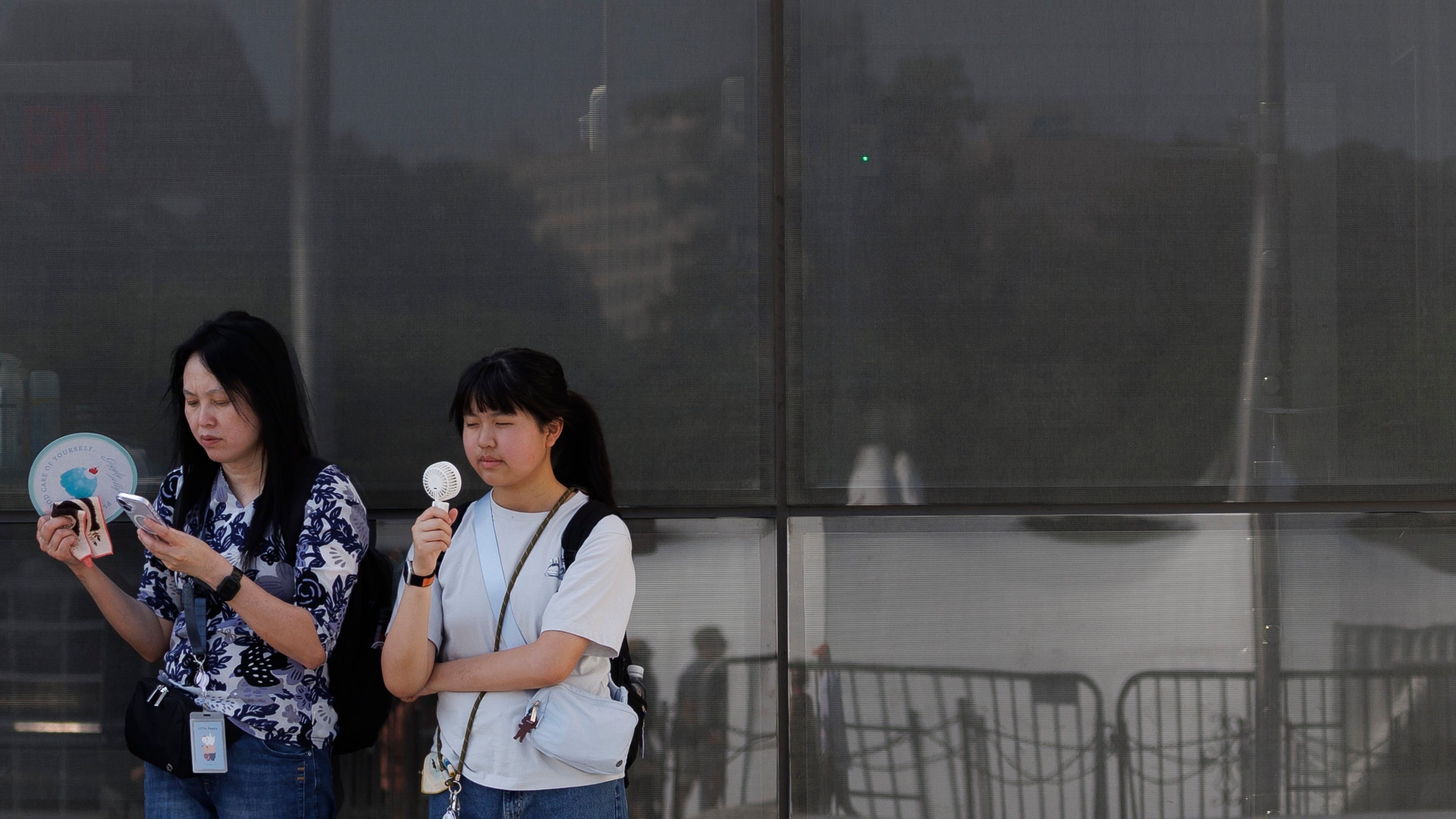 FILE - Visitors use fans as as they wait to enter the Washington Monument, July 1, 2026, in Washington. (AP Photo/Tom Brenner, File)