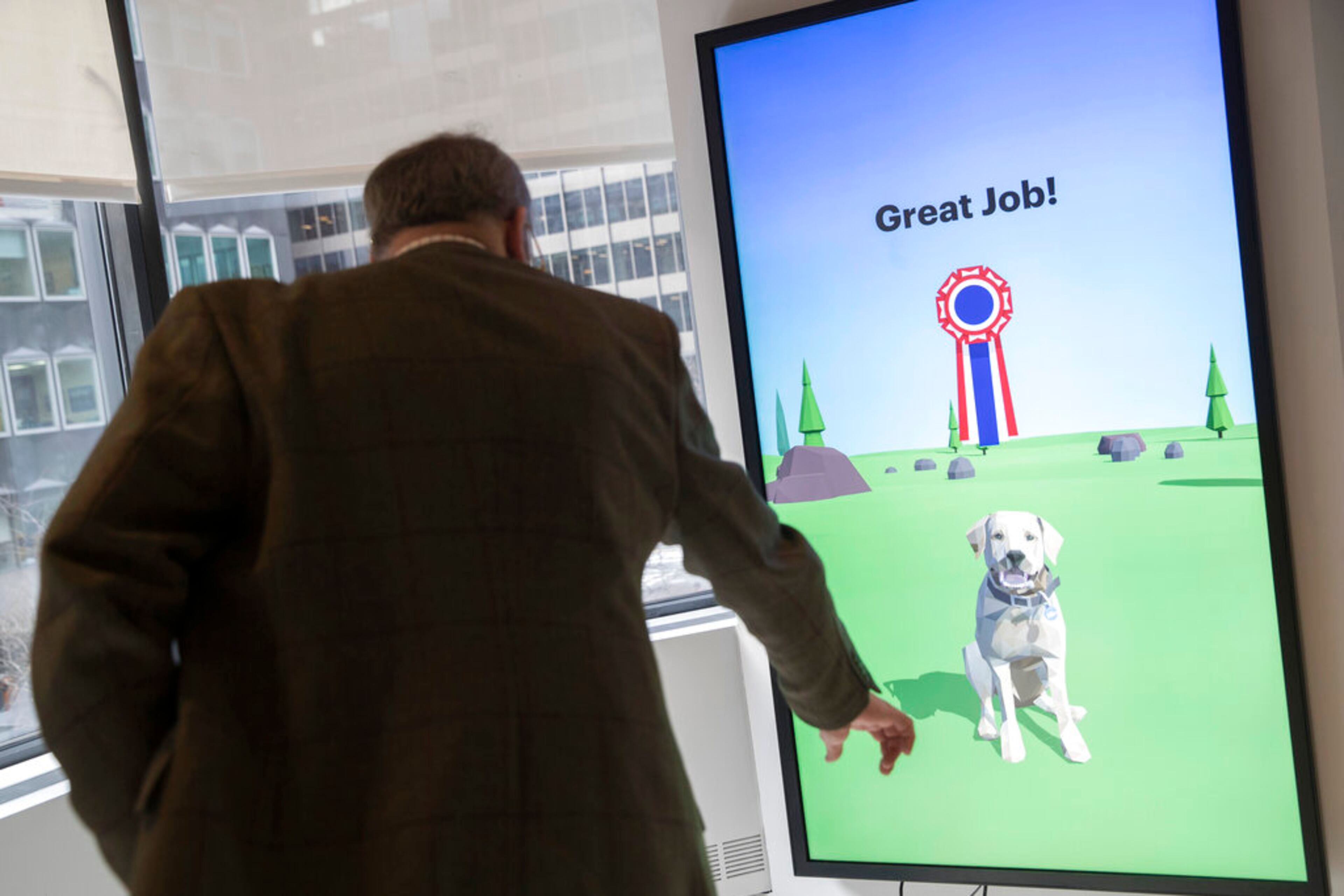 This Wednesday, Jan. 9, 2019, photo shows American Kennel Club Museum of the Dog's Executive Director Alan Fausel demonstrating the Basic Dog Training interactive kiosk with a virtual puppy during a tour of the museum in New York. The museum opens Feb. 8. (AP Photo/Mary Altaffer)
