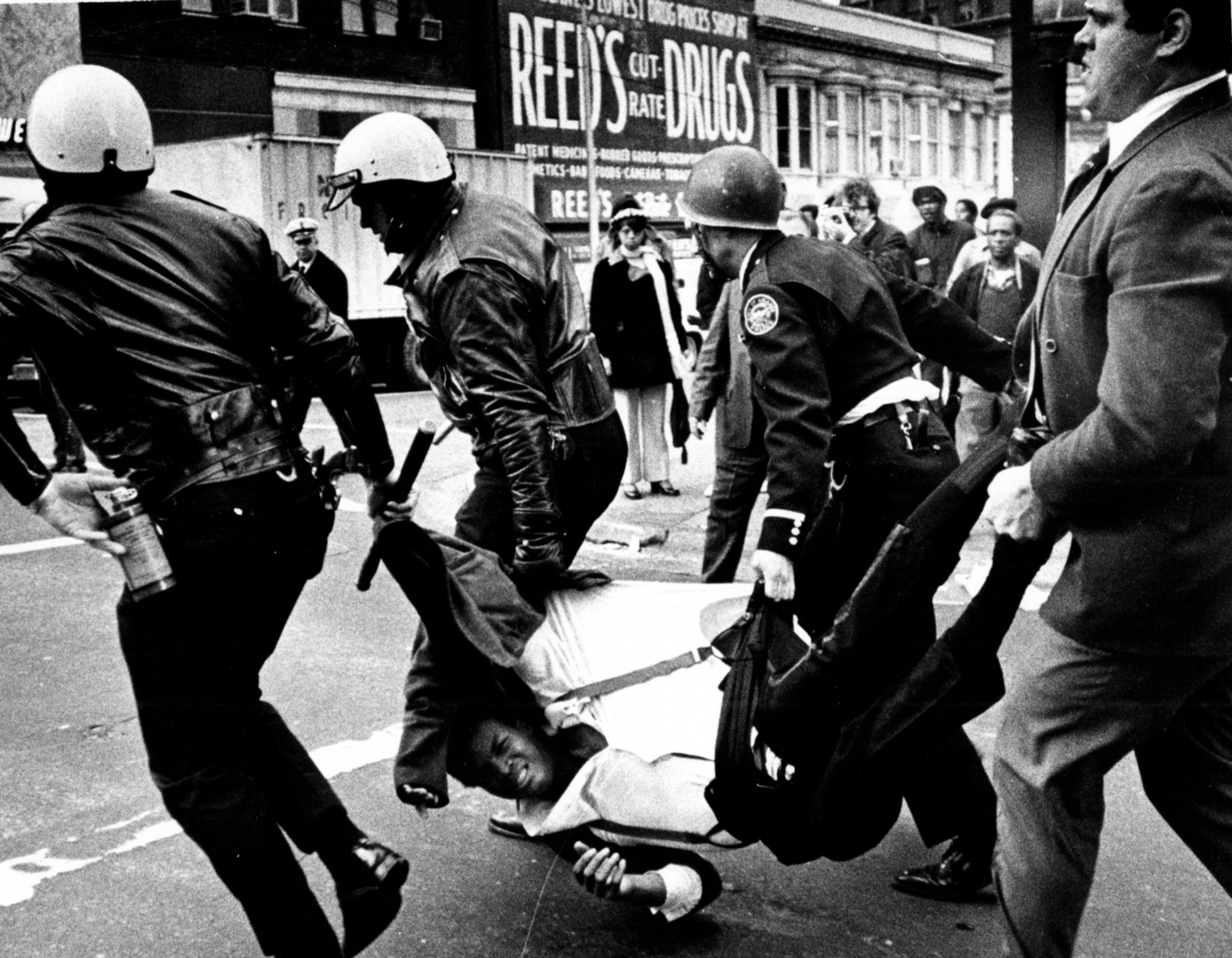 Downtown street fight stirs wild melee in Atlanta on Feb. 15, 1971. Man is carried off by Atlanta policemen on Broad Street.