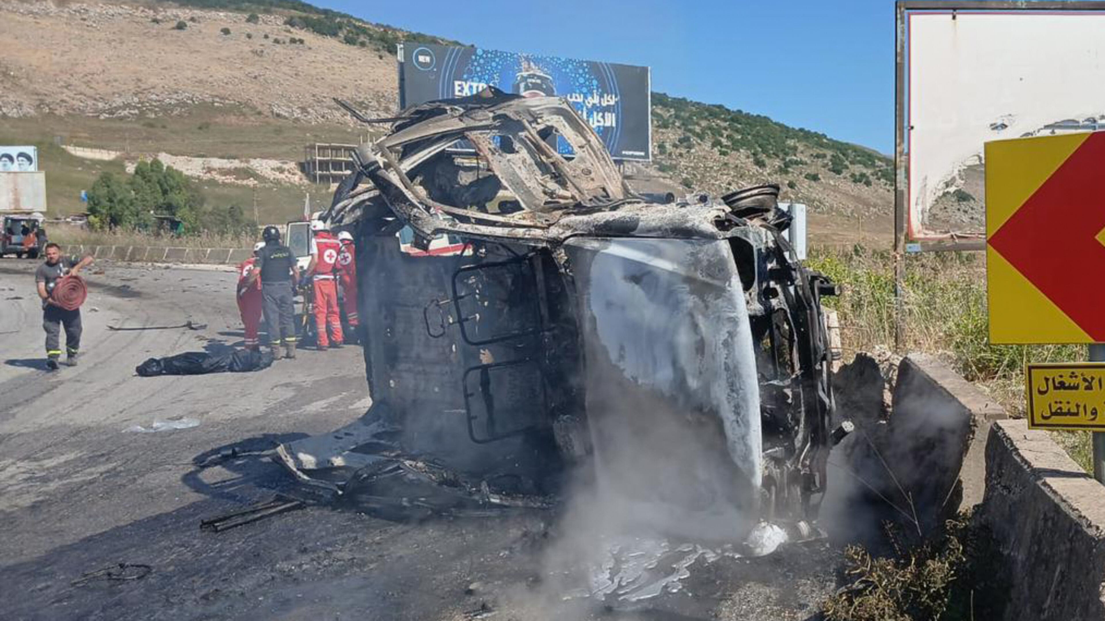 In this image released by the Lebanese Army on its official X account, Lebanese Red Cross personnel and rescue workers stand next to a destroyed vehicle after an Israeli airstrike on the road linking the city of Nabatiyeh and the town of Marjayoun, in Kfar Tebnit, Lebanon, Saturday, June 6, 2026, where, the Lebanese Army said, the vehicle belonged to the army and a brigadier general, a captain and another soldier were killed in the strike. (Lebanese Army via AP)