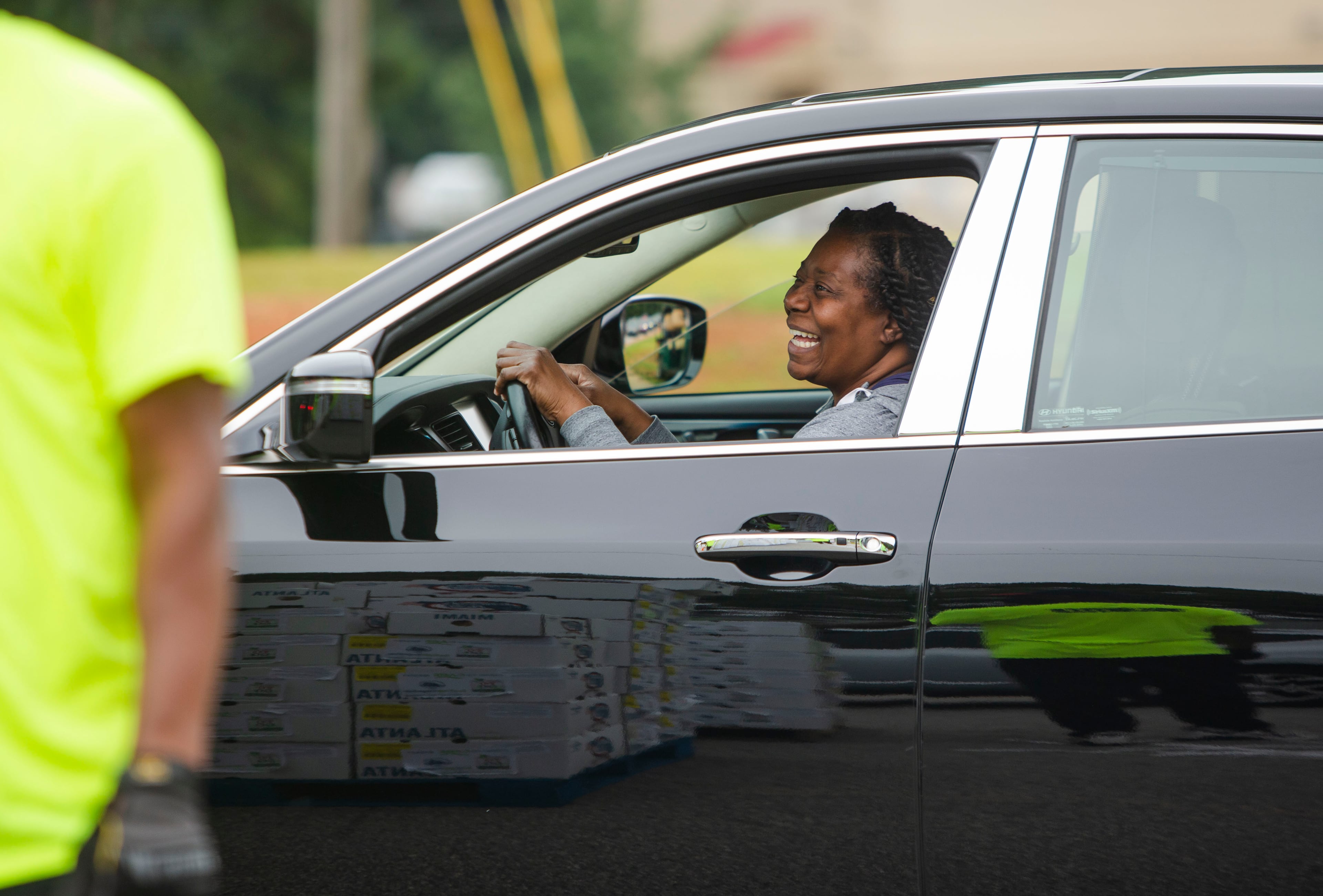 A food recipient smiles while volunteers quickly load the vehicle during a food giveaway event at Berean Christian Church on Saturday, August 27, 2022, in Stone Mountain. The DeKalb County event, at which officials said 5,000 boxes containing about $45 worth of food was distributed, is aimed at easing the burden of inflation-fueled spikes in grocery prices. CHRISTINA MATACOTTA FOR THE ATLANTA JOURNAL-CONSTITUTION.
