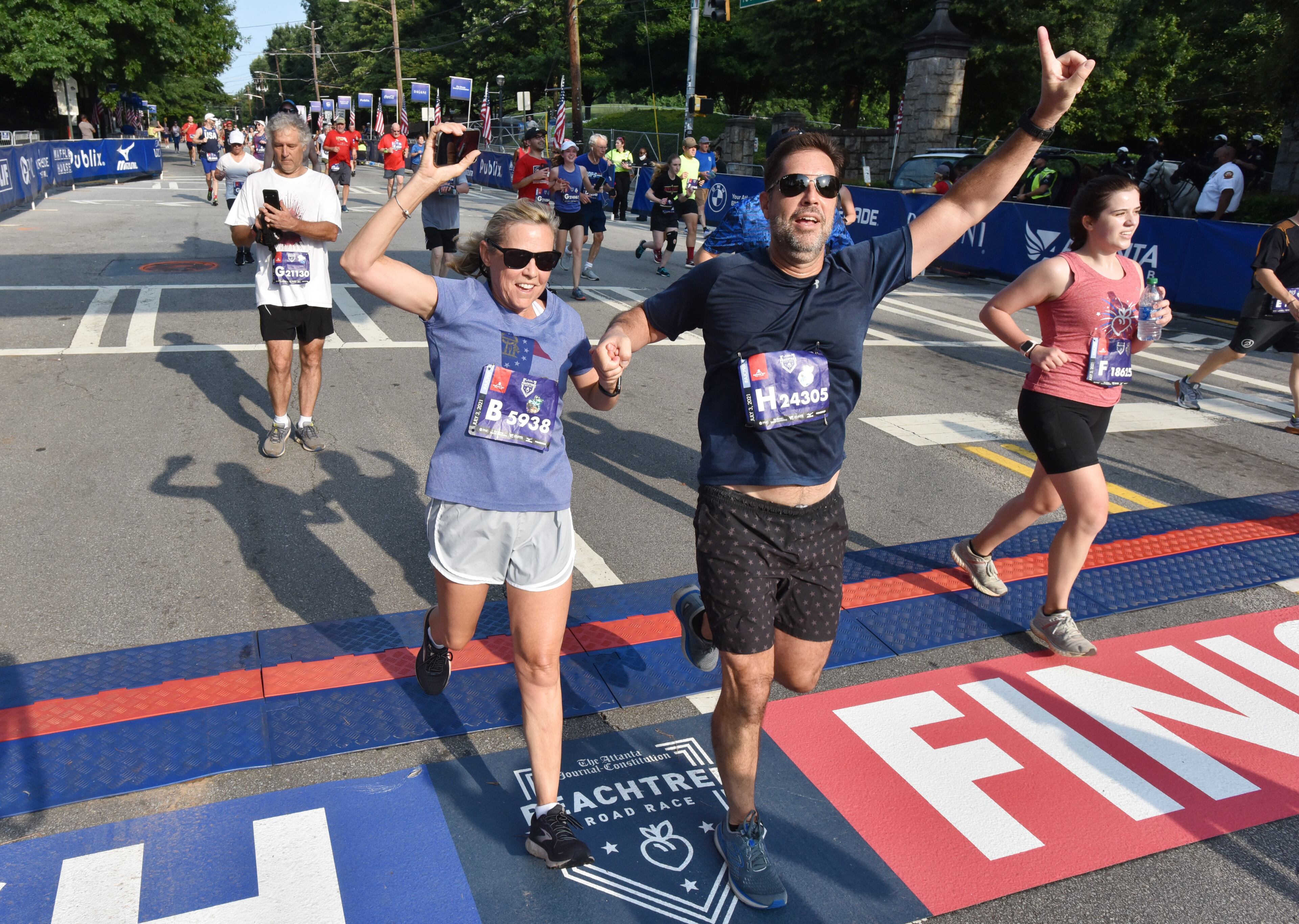July 3, 2021 Atlanta - Runners celebrate as they cross the finish line during the first day of 2021 Atlanta Journal-Constitution Peachtree Road Race on Saturday, July 3, 2021. (Hyosub Shin / Hyosub.Shin@ajc.com)