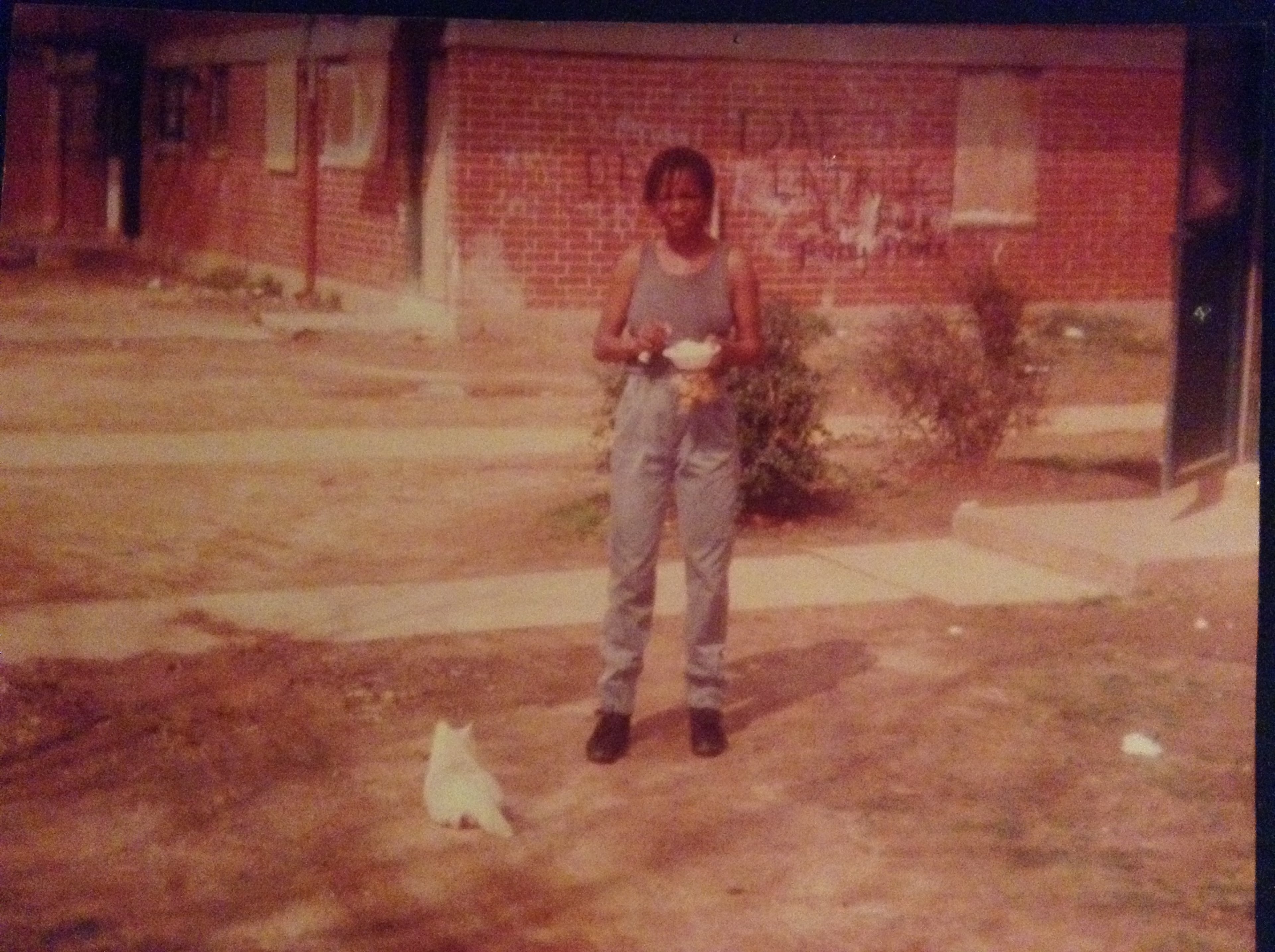 Singleton's mother, Cat, stands in front of their graffiti-covered apartment at Perry Homes a couple of months before her death.