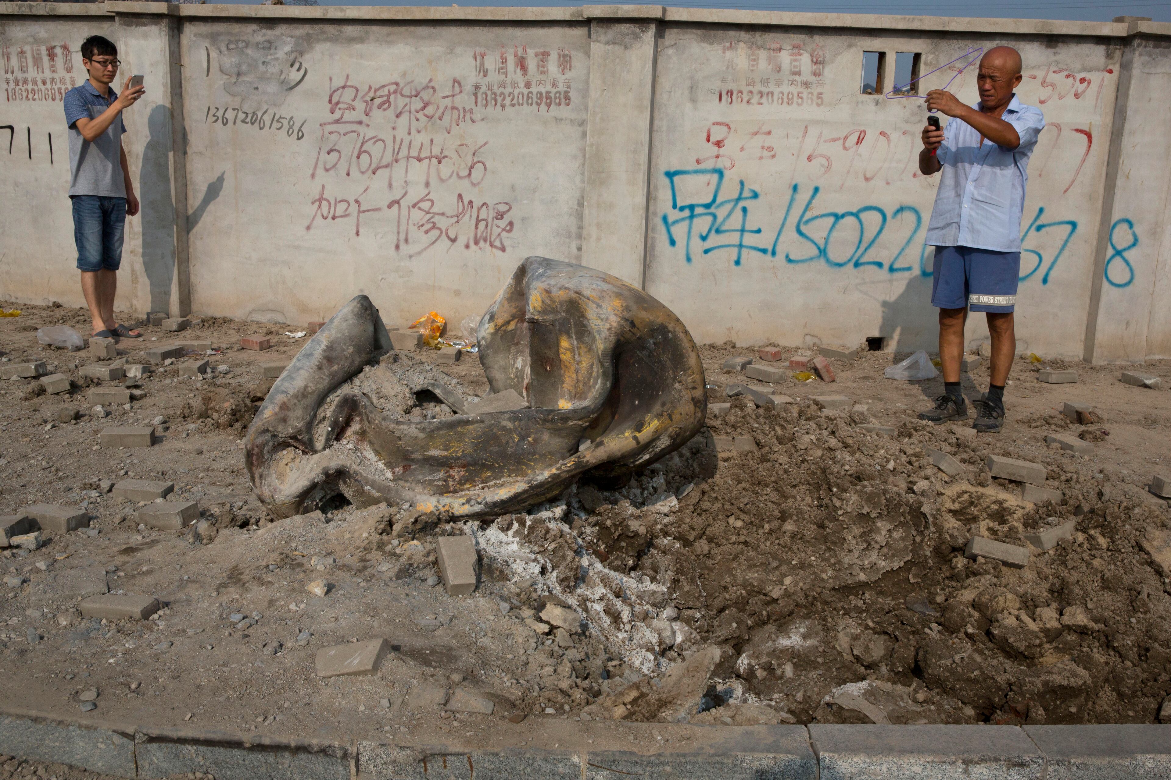 Residents take photos of what appears to be a metal container thrown several kilometers from the site of an explosion in northeastern China's Tianjin municipality Aug. 13, 2015.