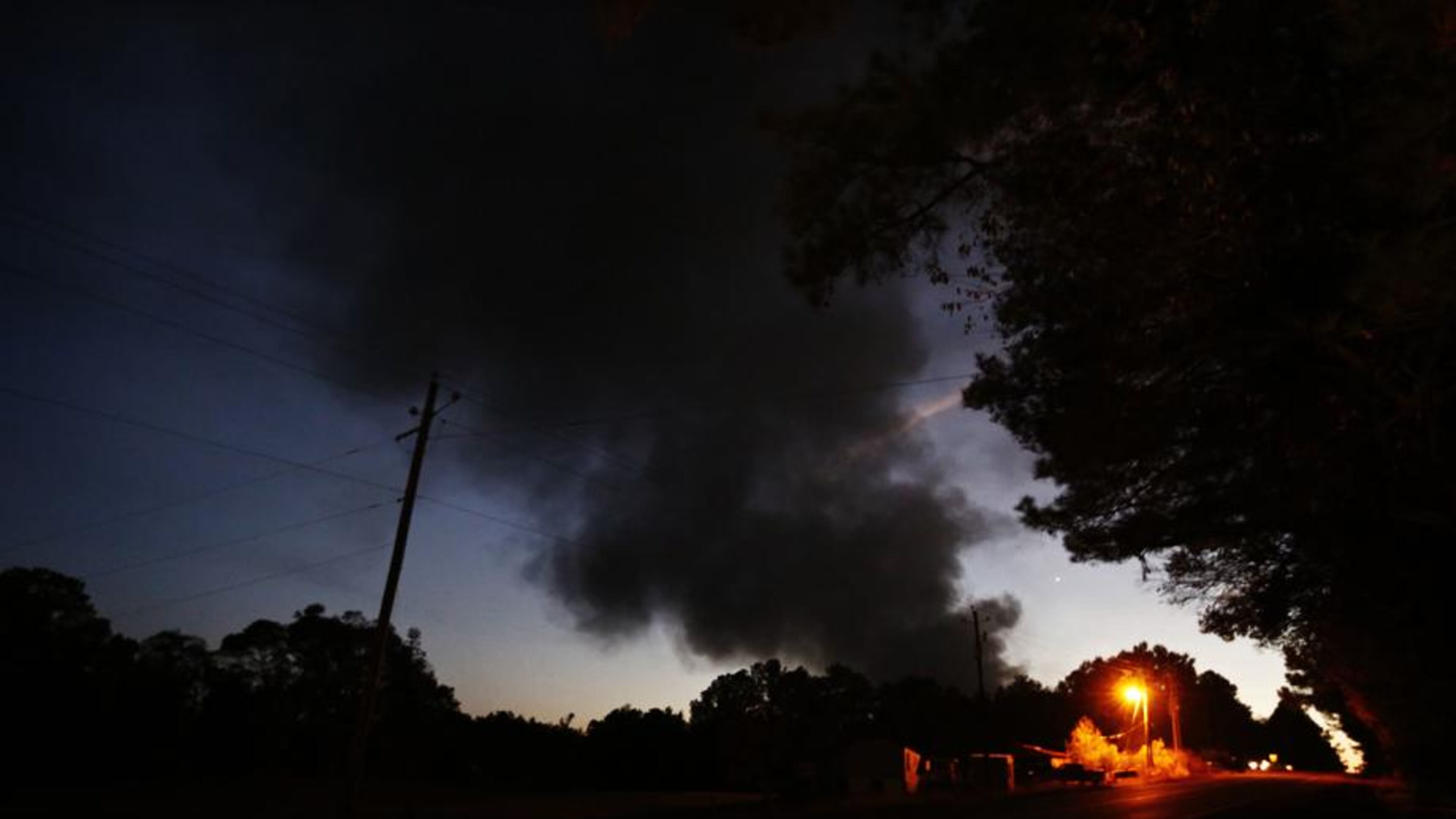 Light from a light pole shows a house near a plume of smoke from a Colonial Pipeline explosion, Monday, Oct. 31, 2016, in Helena, Ala. Colonial Pipeline said in a statement that it has shut down its main pipeline in Alabama after the explosion in a rural part of the state outside Birmingham. (AP Photo/Brynn Anderson)