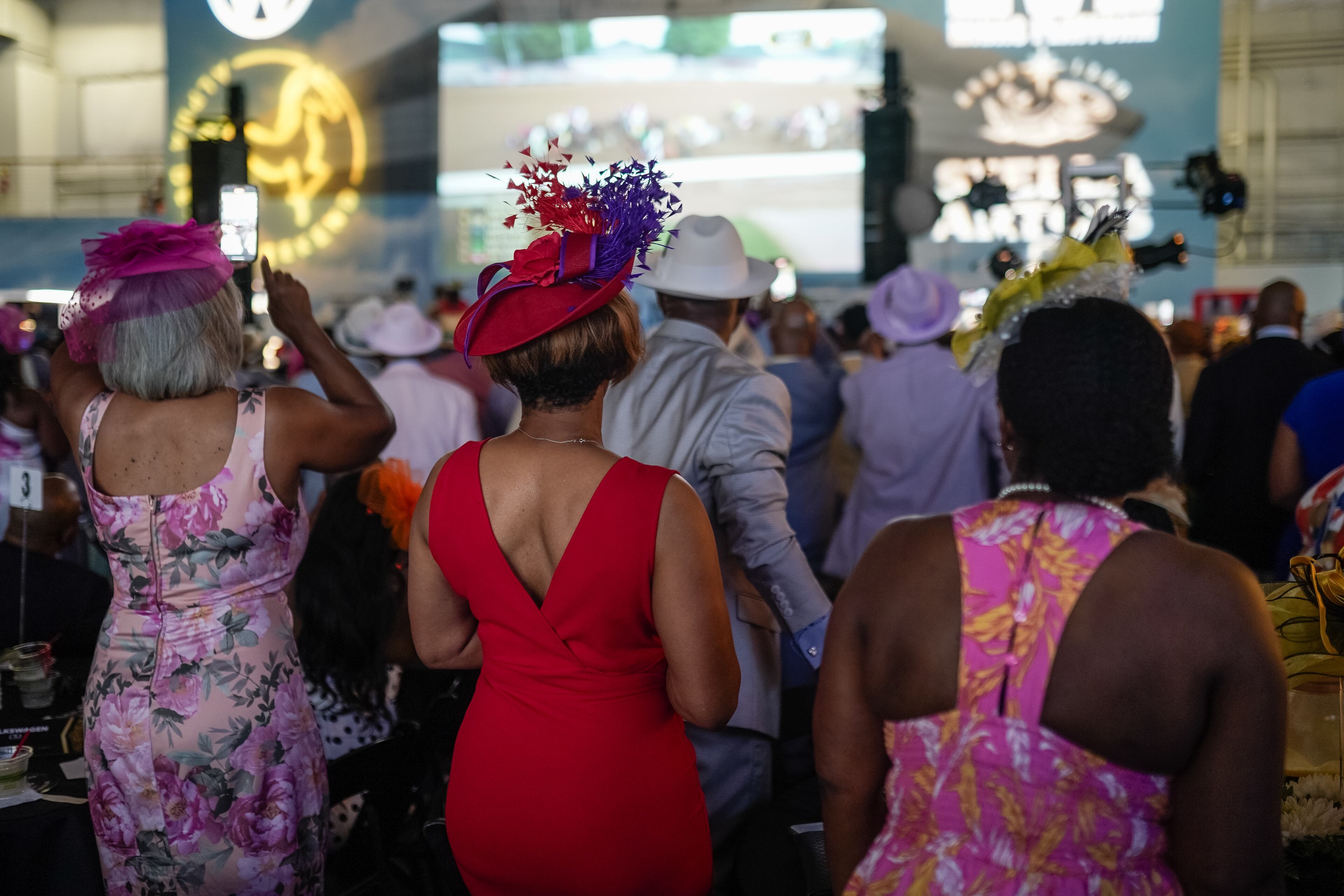 Attendees watch the Kentucky Derby at the Alpha Derby, a Kentucky-Derby-themed event that raises thousands for scholarships, at the Delta Flight Museum on Saturday, May 4, 2024, in Atlanta. (Elijah Nouvelage for The Atlanta Journal-Constitution)