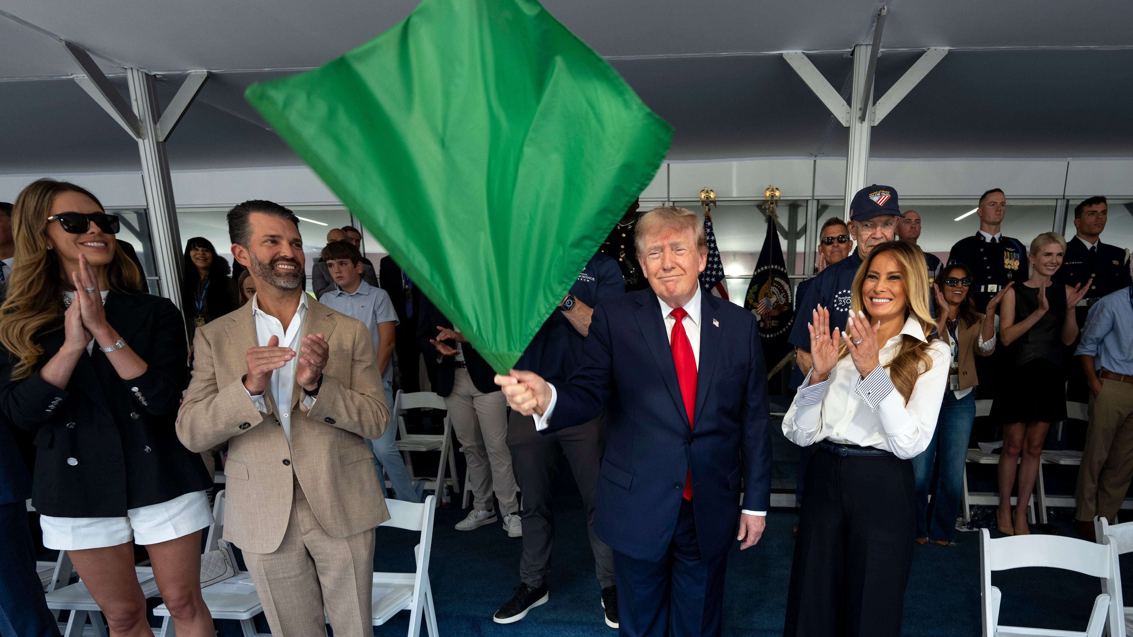 President Donald Trump waves the green flag to start the race alongside first lady Melania Trump, right, and from left, Bettina Trump and Donald Trump Jr. during the IndyCar Freedom 250 Grand Prix auto race, Sunday, Aug. 23, 2026, in Washington. (Doug Mills/The New York Times via AP, Pool)