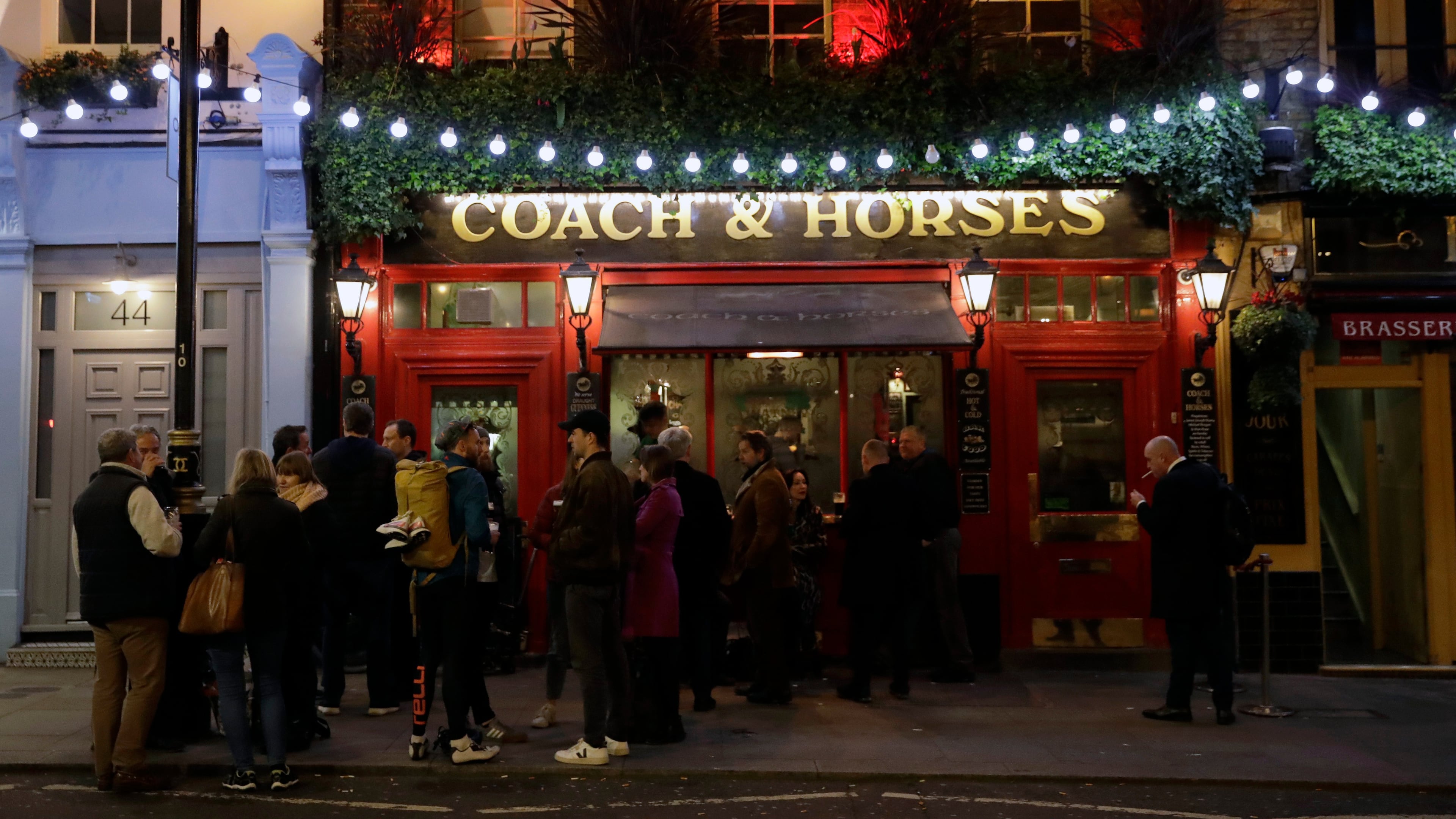 FILE - People stand drinking outside the Coach & Horses pub on Saint Patrick's Day in the Covent Garden district of central London, which is a popular tourist area, Tuesday, March 17, 2020. (AP Photo/Matt Dunham, file)
